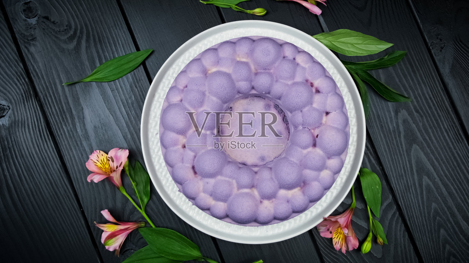 蓝莓素芝士蛋糕。黑色背景，白色盘子上放着新鲜浆果的生蛋糕。平躺照片摄影图片