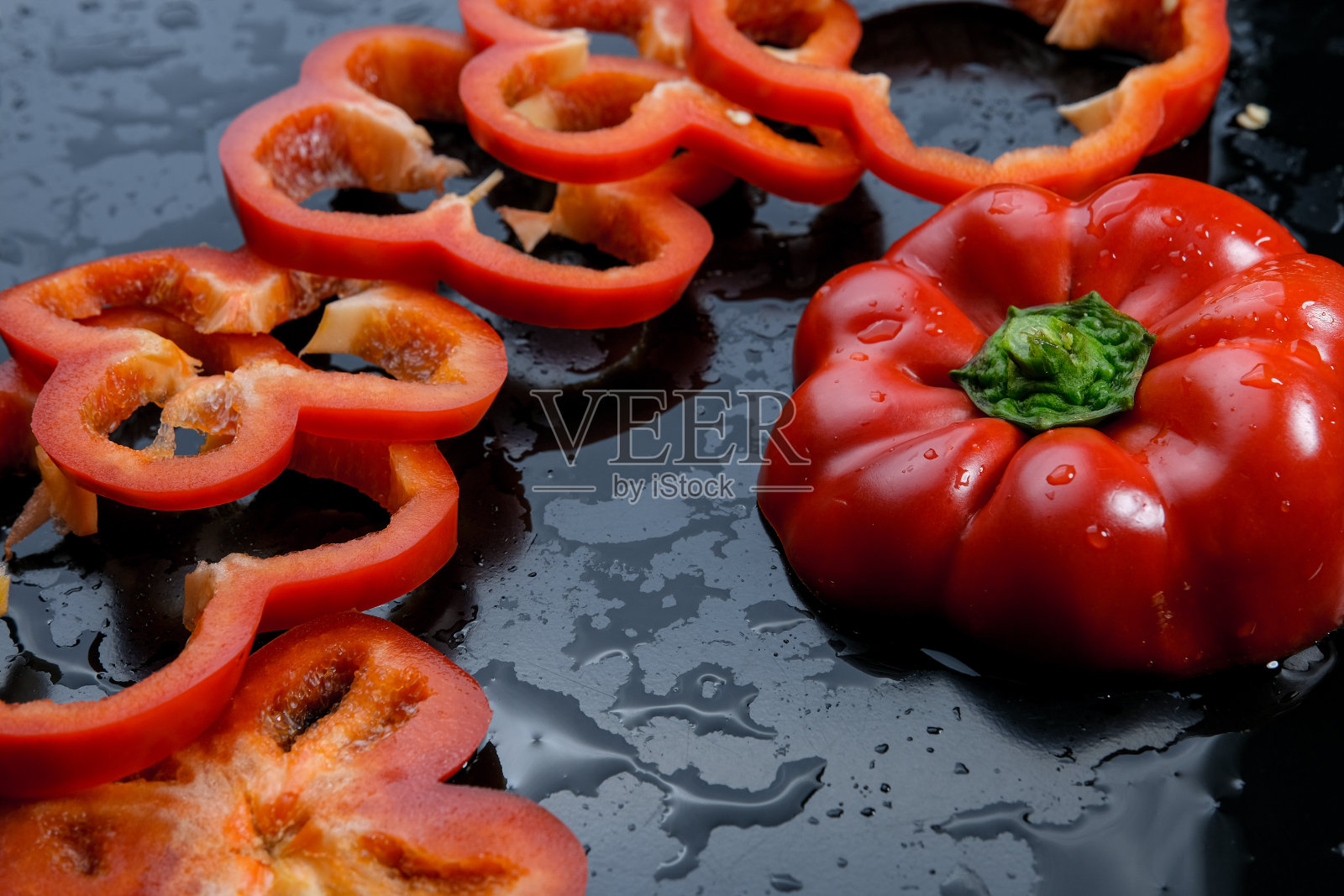 三片橙子和红灯笼椒。黑色背景。照片摄影图片