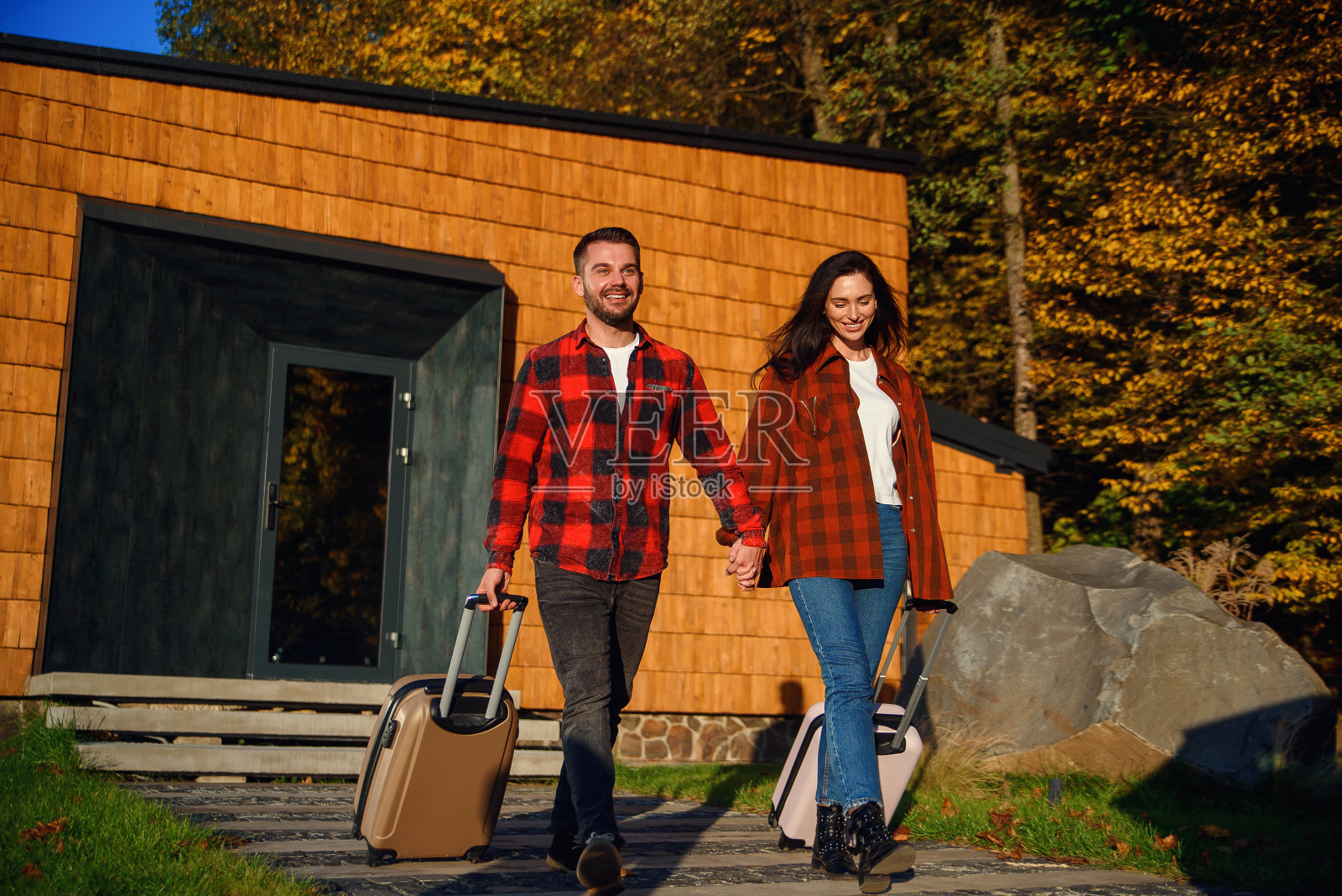 英俊的大胡子男人和漂亮时髦的女人带着手提箱出门旅行。照片摄影图片