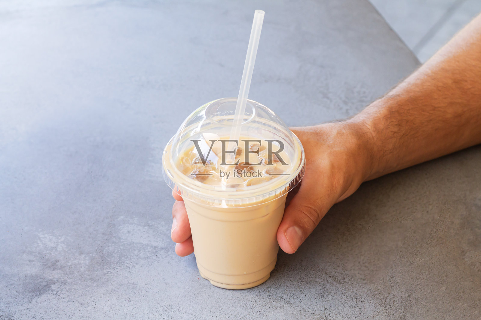 一名男子拿着冰咖啡或拿铁在带走的塑料杯在街头咖啡馆照片摄影图片