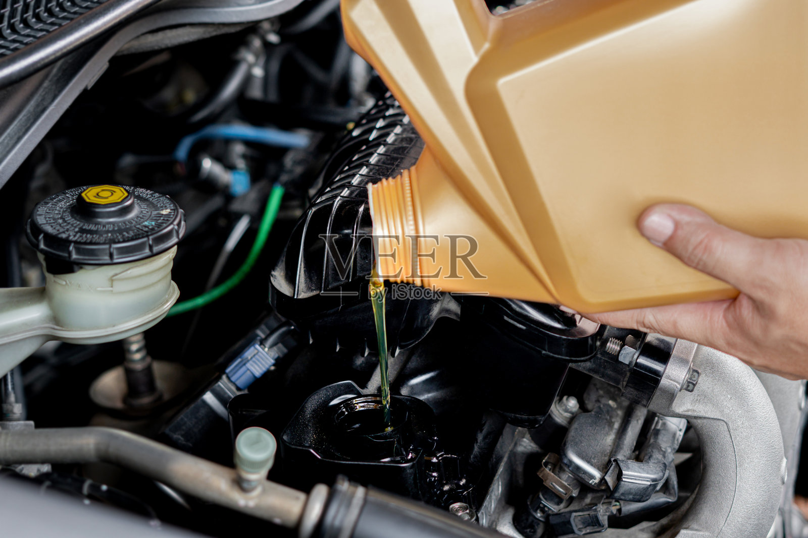 一个人正在给汽车引擎加油。在发动机汽车保养中添加发动机油:汽车能源燃料和服务理念照片摄影图片