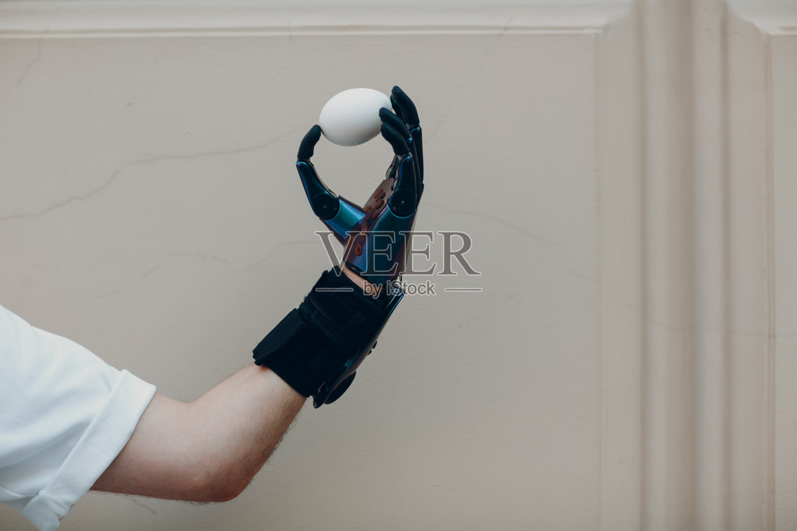 年轻的残疾男子用假手拿着鸡蛋，穿着休闲装。照片摄影图片