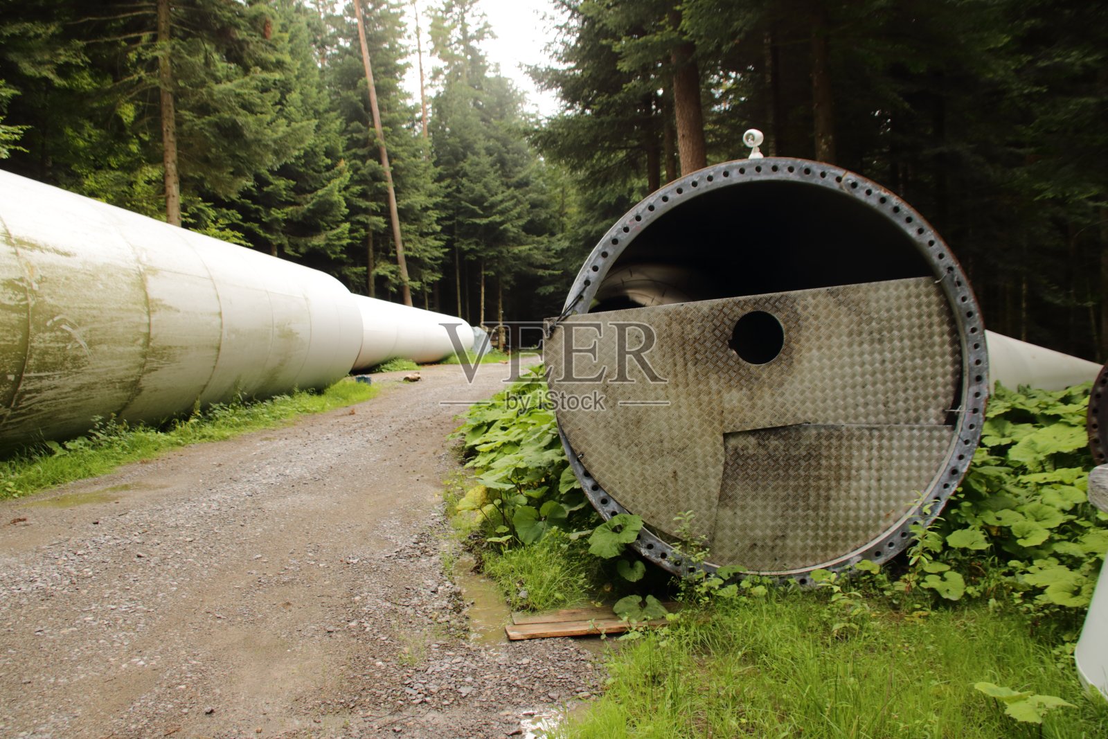 一个旧风力涡轮机的桅杆被储存在森林里等着搬走照片摄影图片