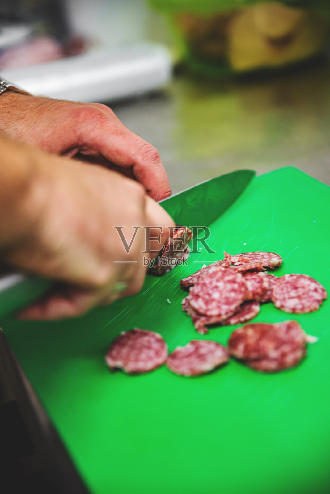 厨师用刀在案板上切萨拉米香肠照片摄影图片