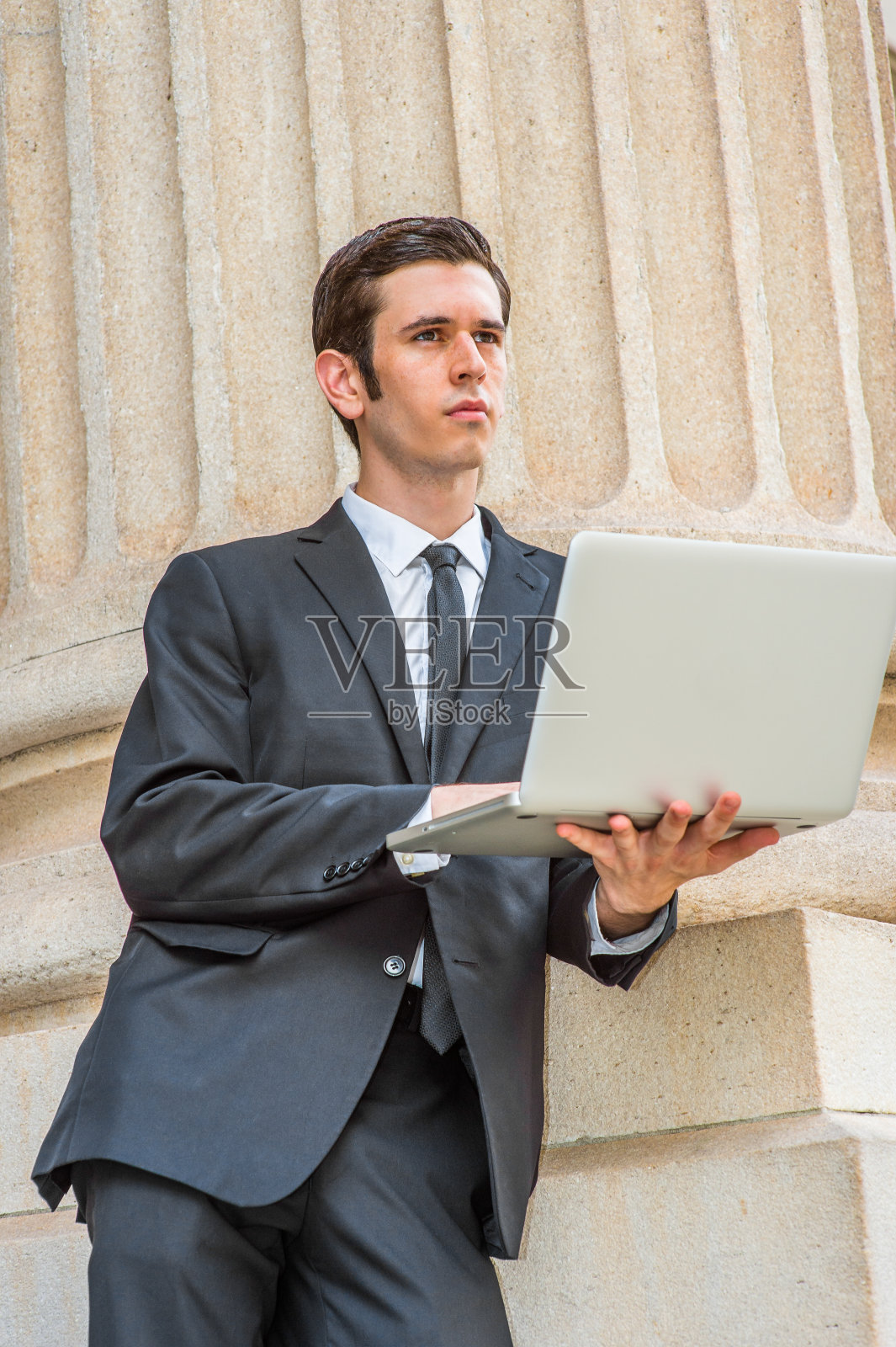 年轻的商人站在纽约市的办公楼外，用笔记本电脑工作照片摄影图片