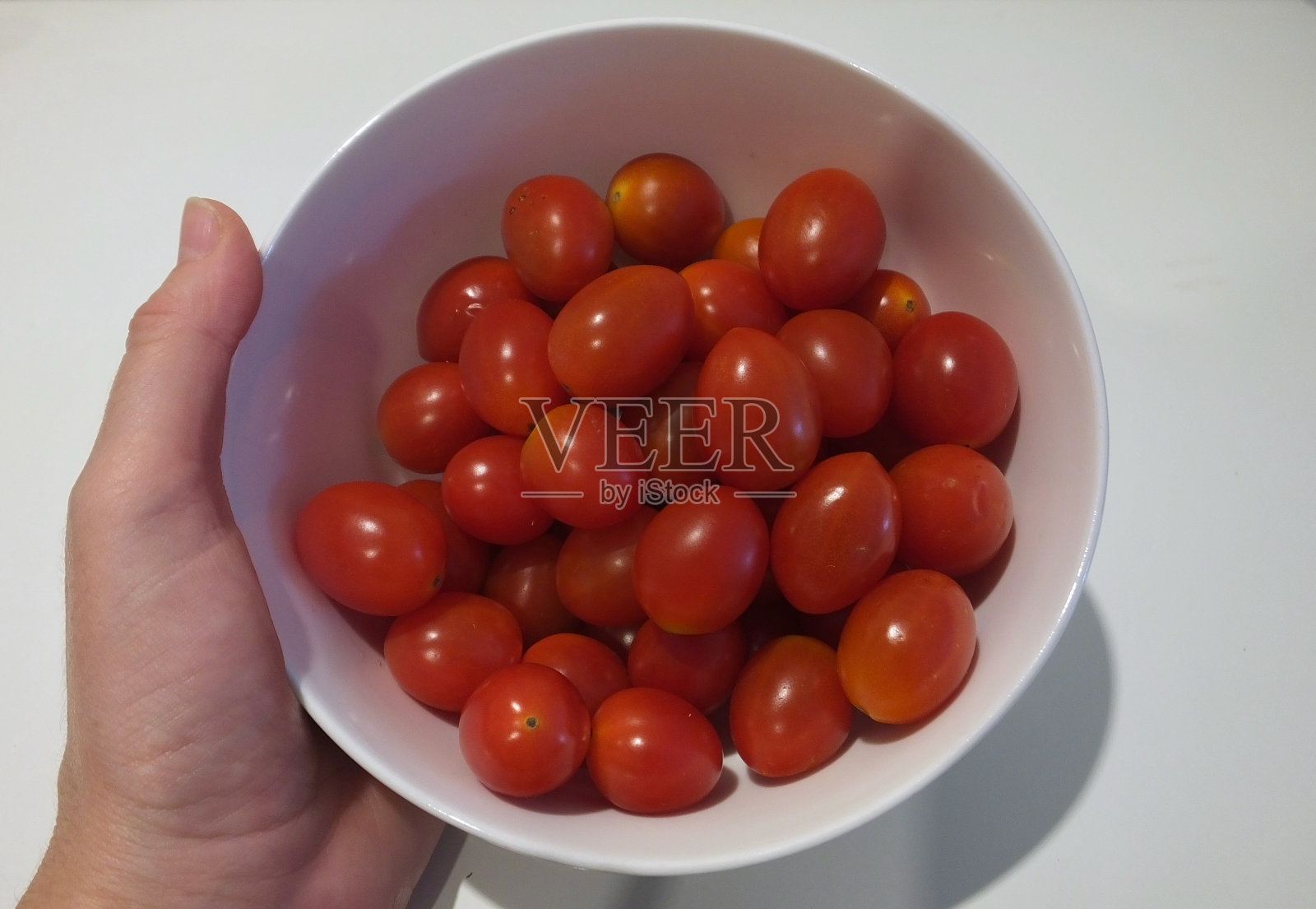 手里拿着一碗白色的圣女果照片摄影图片