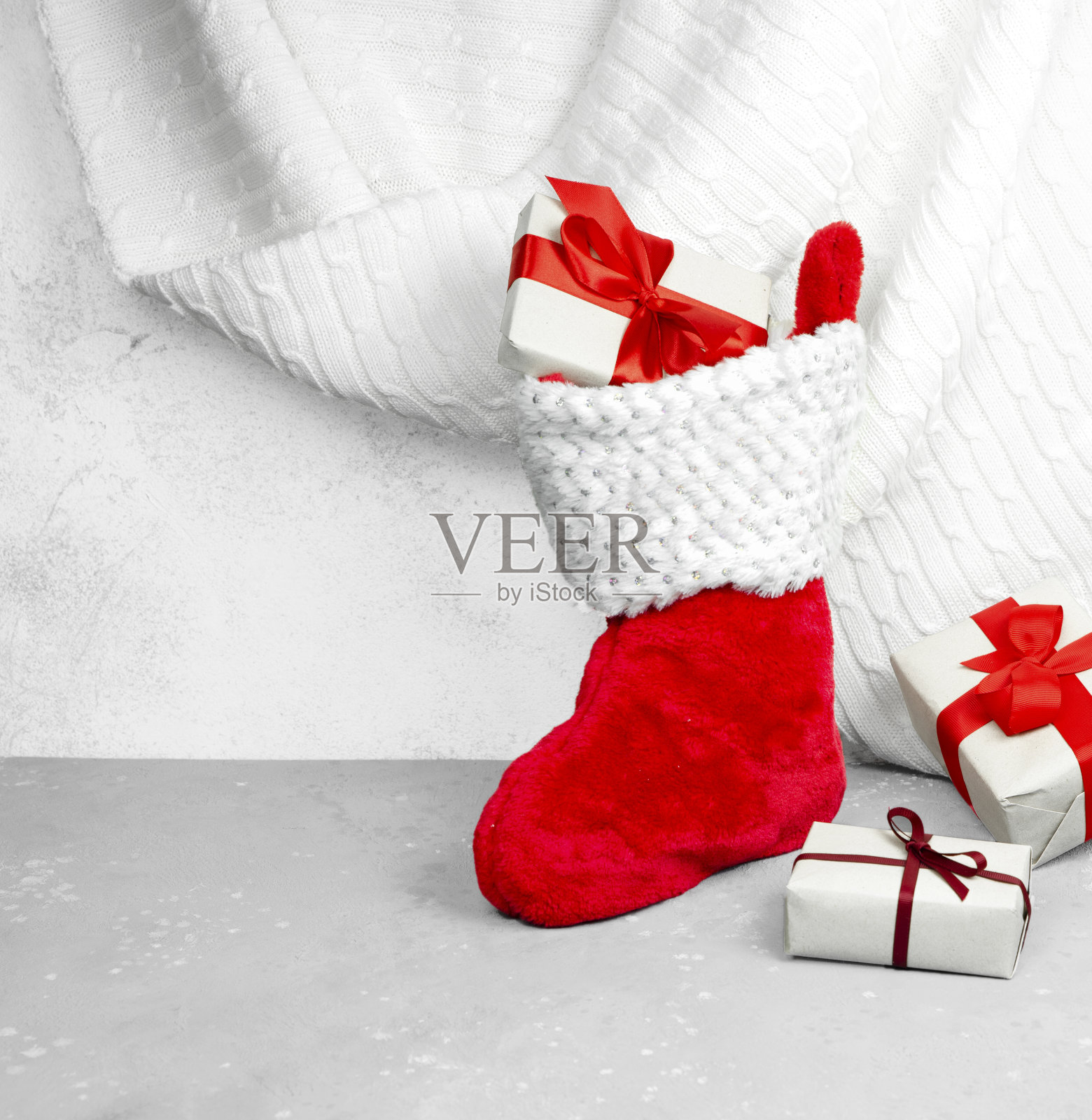 圣诞袜红色，白色格子与礼物在灰色背景。照片摄影图片