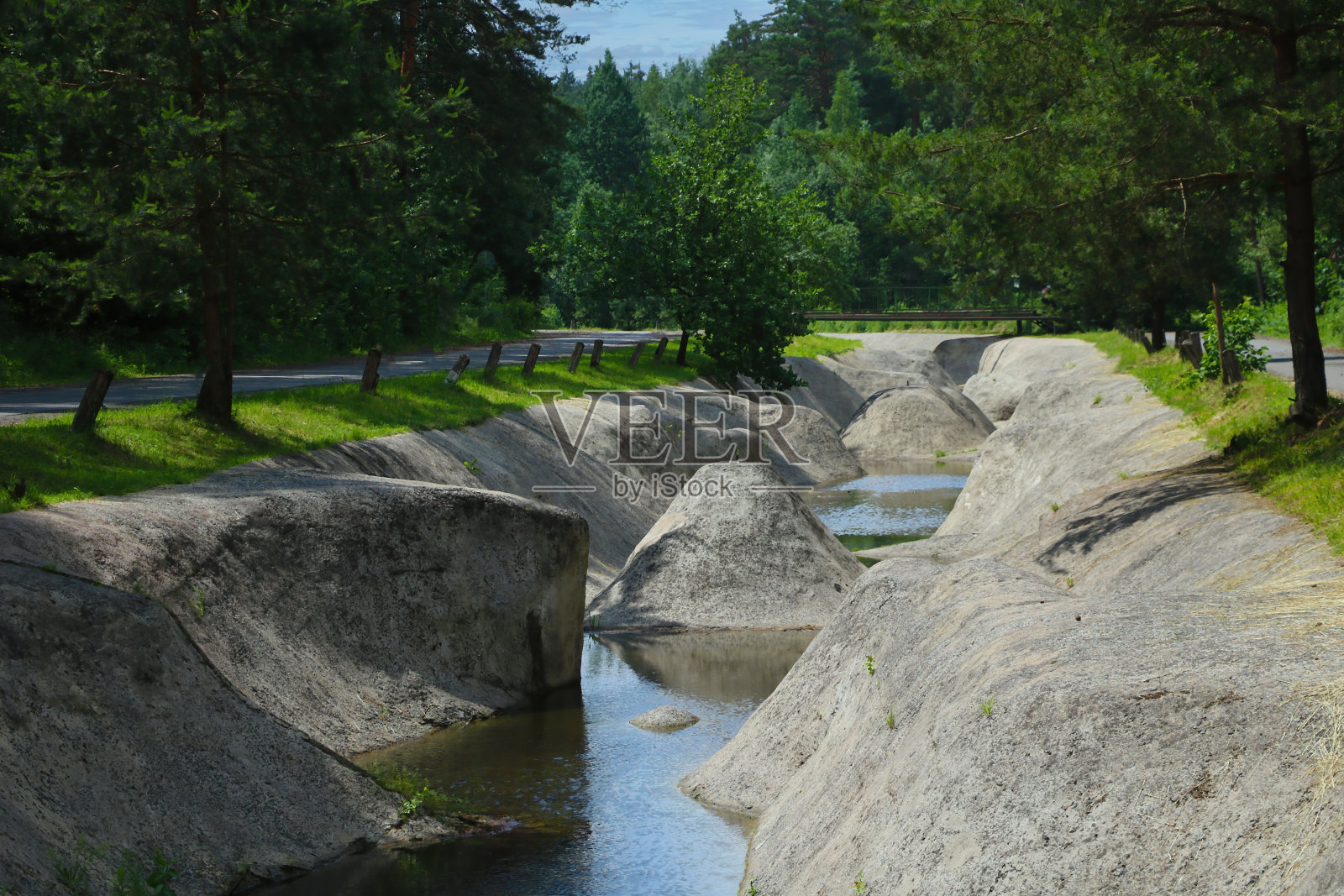 一条在阳光明媚的日子里没有水的人造运河。照片摄影图片