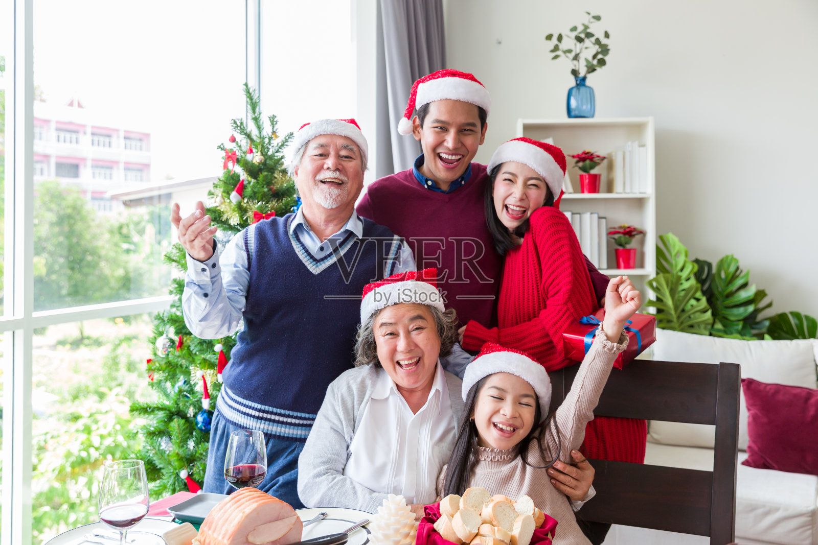 快乐的亚洲家庭在圣诞节戴着圣诞帽共进午餐照片摄影图片