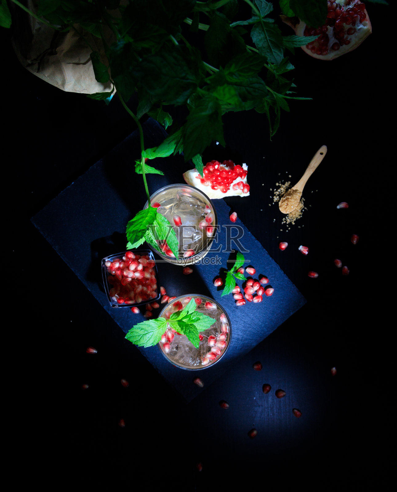 两杯加了石榴、薄荷和糖的夏季饮料。平铺和黑色背景照片摄影图片