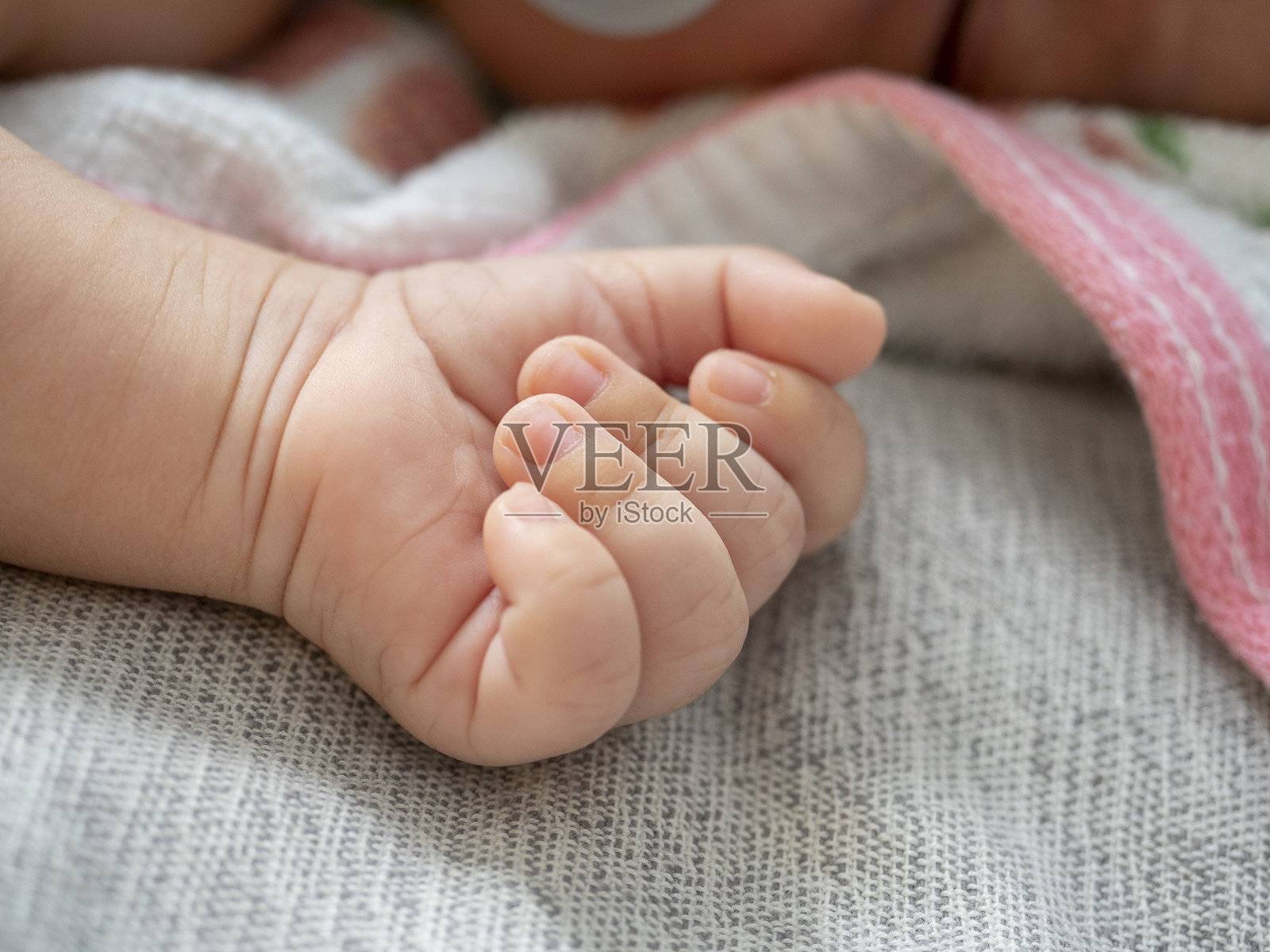 一个新生婴儿的小手躺在灰色的毯子上。小孩照片摄影图片