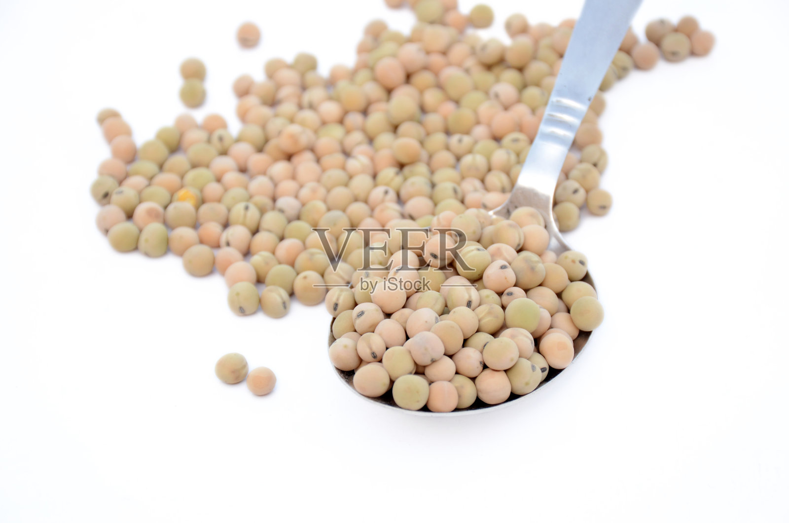将黄褐色的豌豆种子捆在白色背景上孤立的勺子里。照片摄影图片