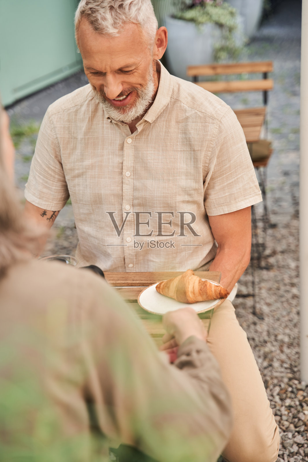 在浪漫的约会中，男人微笑着和他的妻子准备吃羊角面包照片摄影图片
