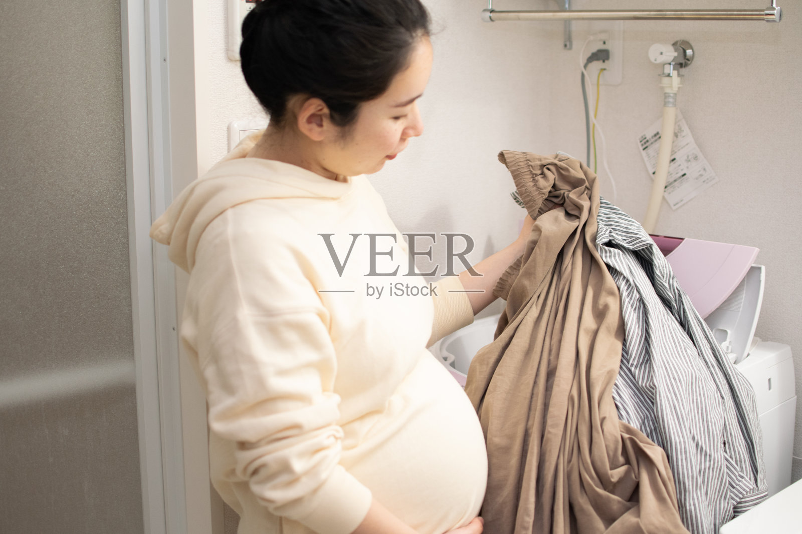 一个年轻的亚洲孕妇在洗衣服照片摄影图片