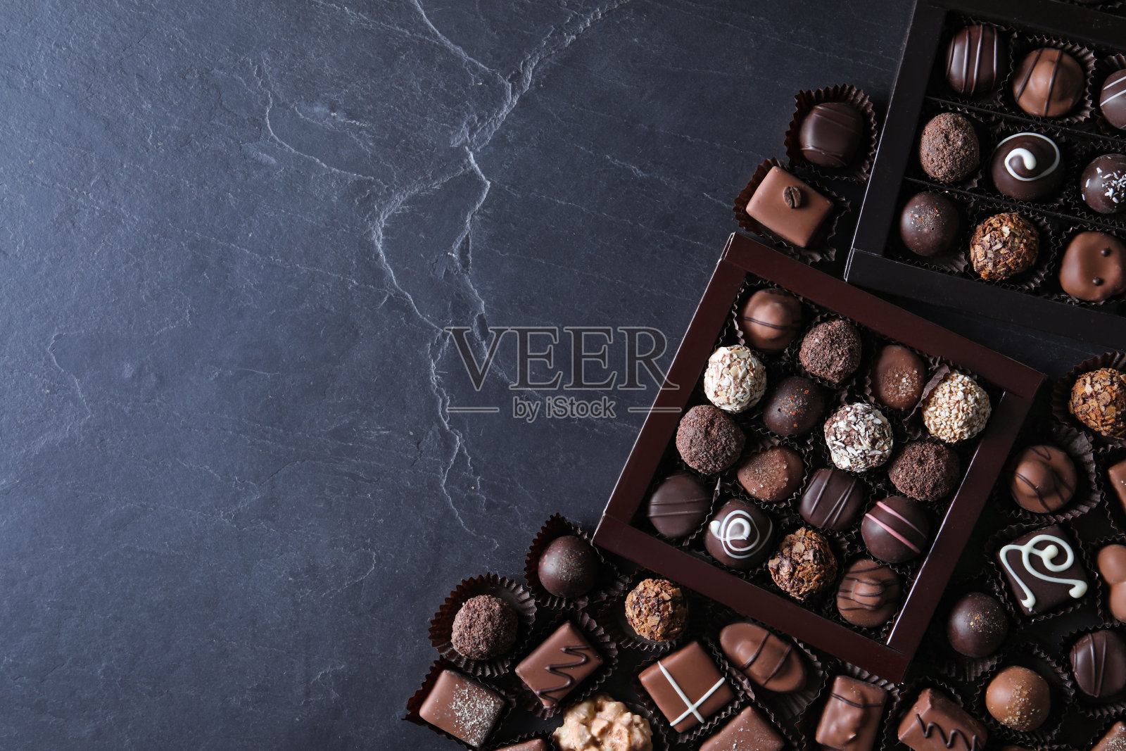 不同美味的巧克力糖果放在黑色的桌子上，平躺着。空间的文本照片摄影图片