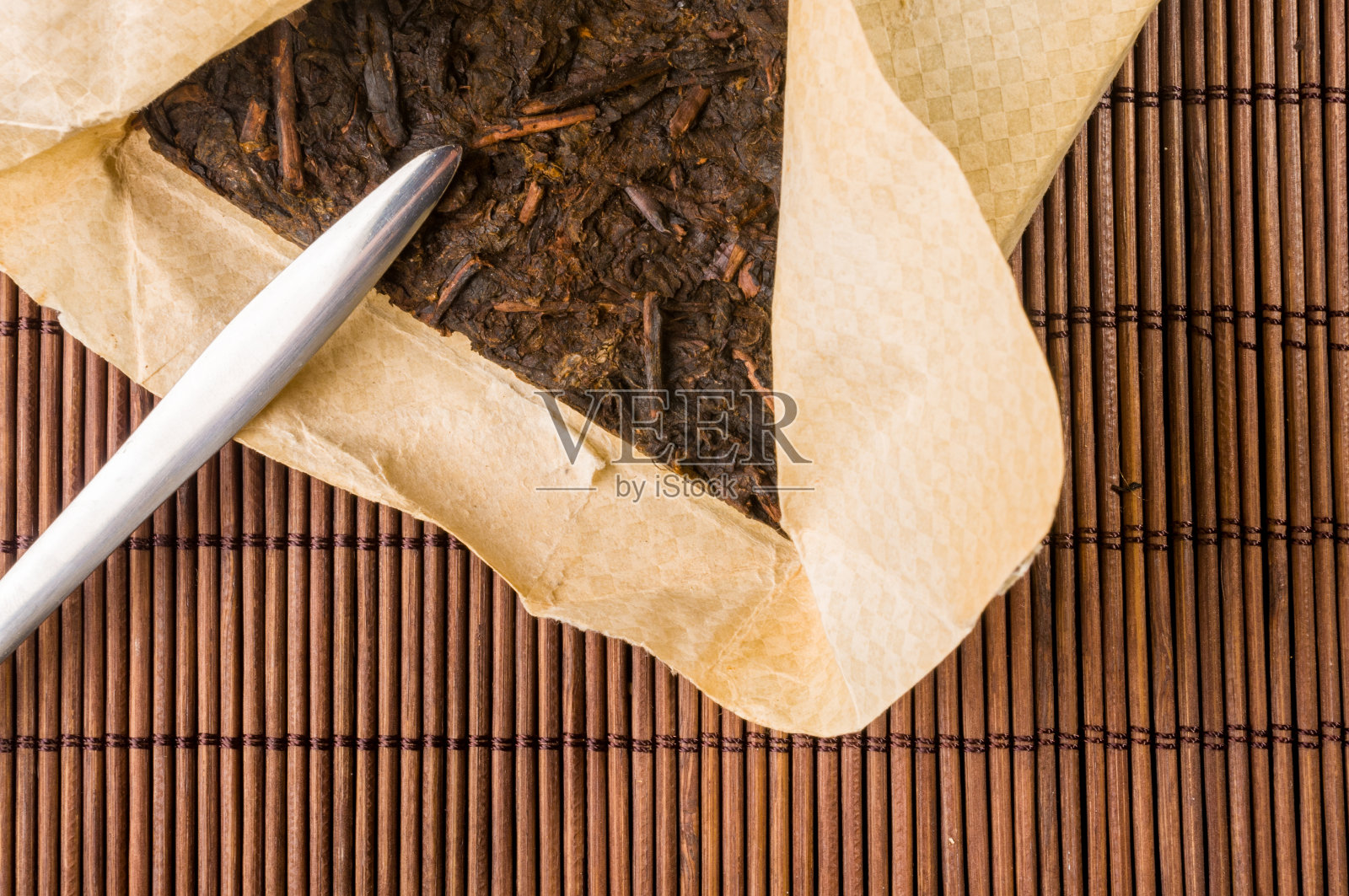 中国人压在包装纸上的普洱茶和竹席上的茶刀，特写，宏观照片摄影图片