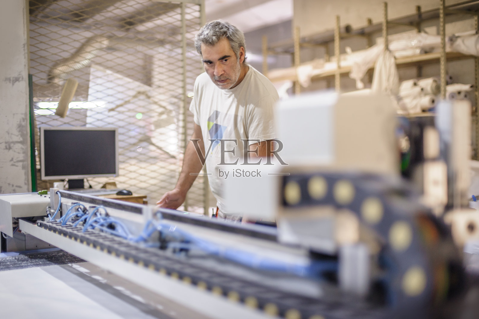 技术人员在数控数字切割机上工作，用于切割纺织品照片摄影图片