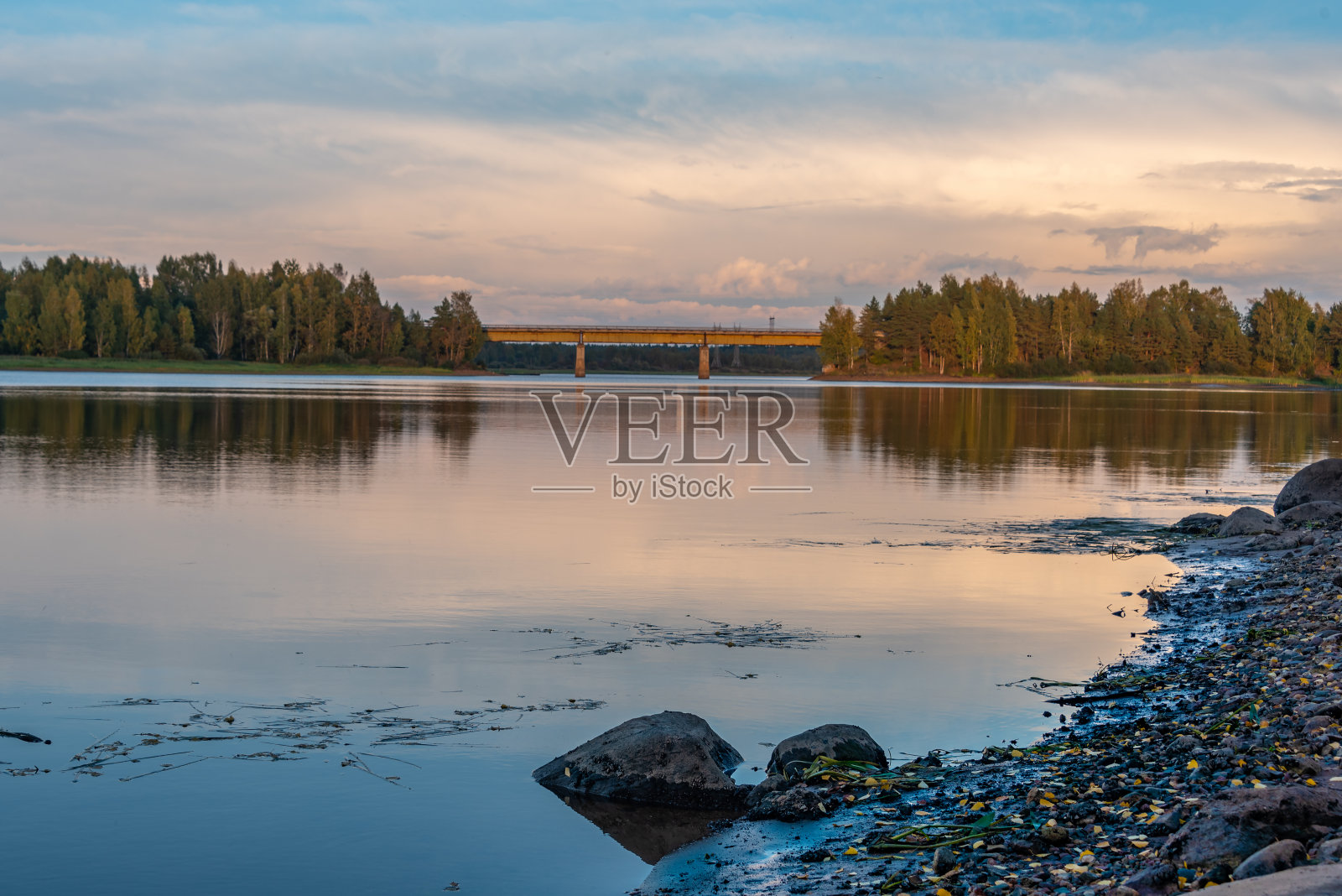 落日映照下的河流和森林。云在水中的倒影。城郊的公路桥穿过这条河。照片摄影图片