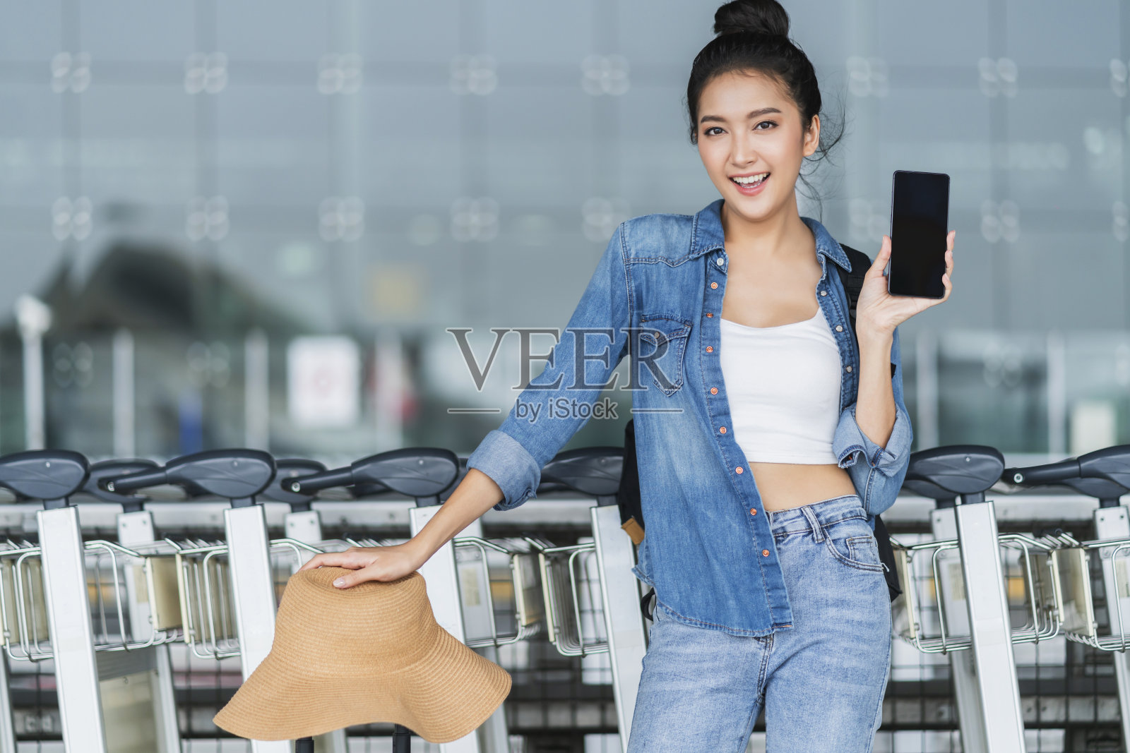 聪明迷人的亚洲女性手持智能手机在应用程序屏幕上查看出租车时刻表智慧城市旅游理念，亚洲女性使用智能手机在终端平台站呼叫出租车照片摄影图片