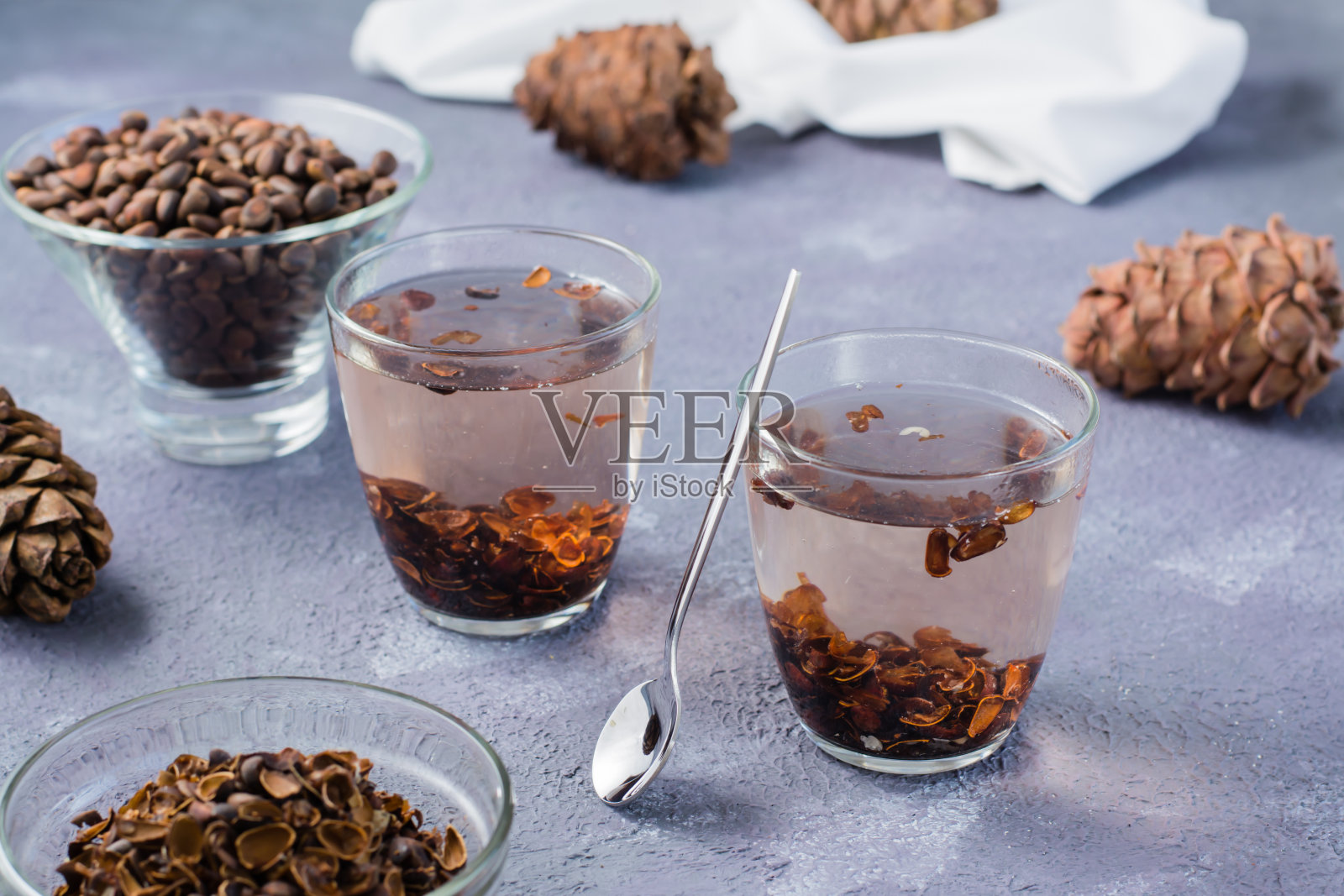 把松子壳泡在玻璃杯里，松子放在桌子上。替代医学。照片摄影图片