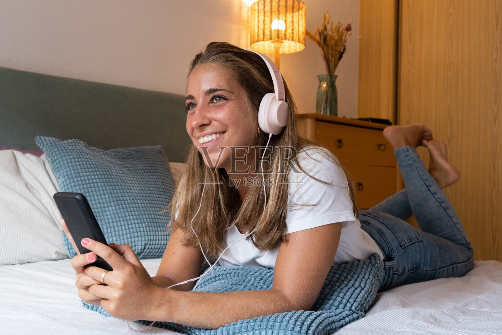 开朗的金发女人在室内使用智能手机。照片摄影图片