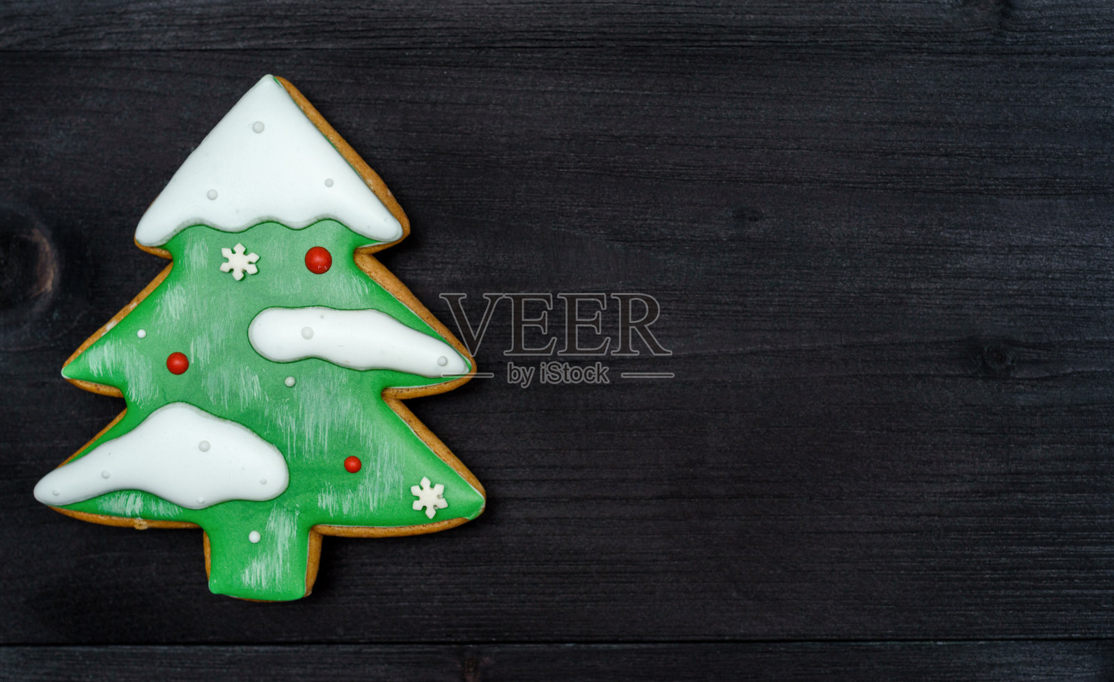 一个圣诞冷杉树姜饼饼干与雪和装饰在深色木制背景，俯视图，平躺。假日美食，极简主义，最小的概念，复制空间照片摄影图片