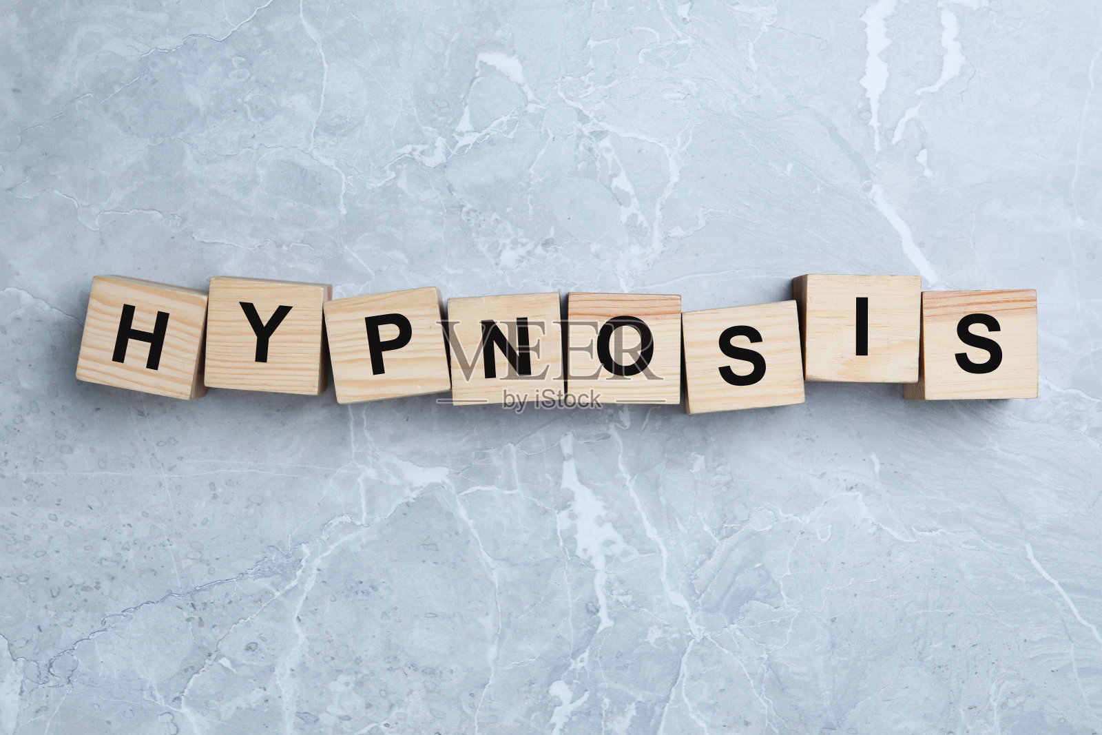 浅灰色大理石背景上有单词HYPNOSIS的木块，平铺照片摄影图片