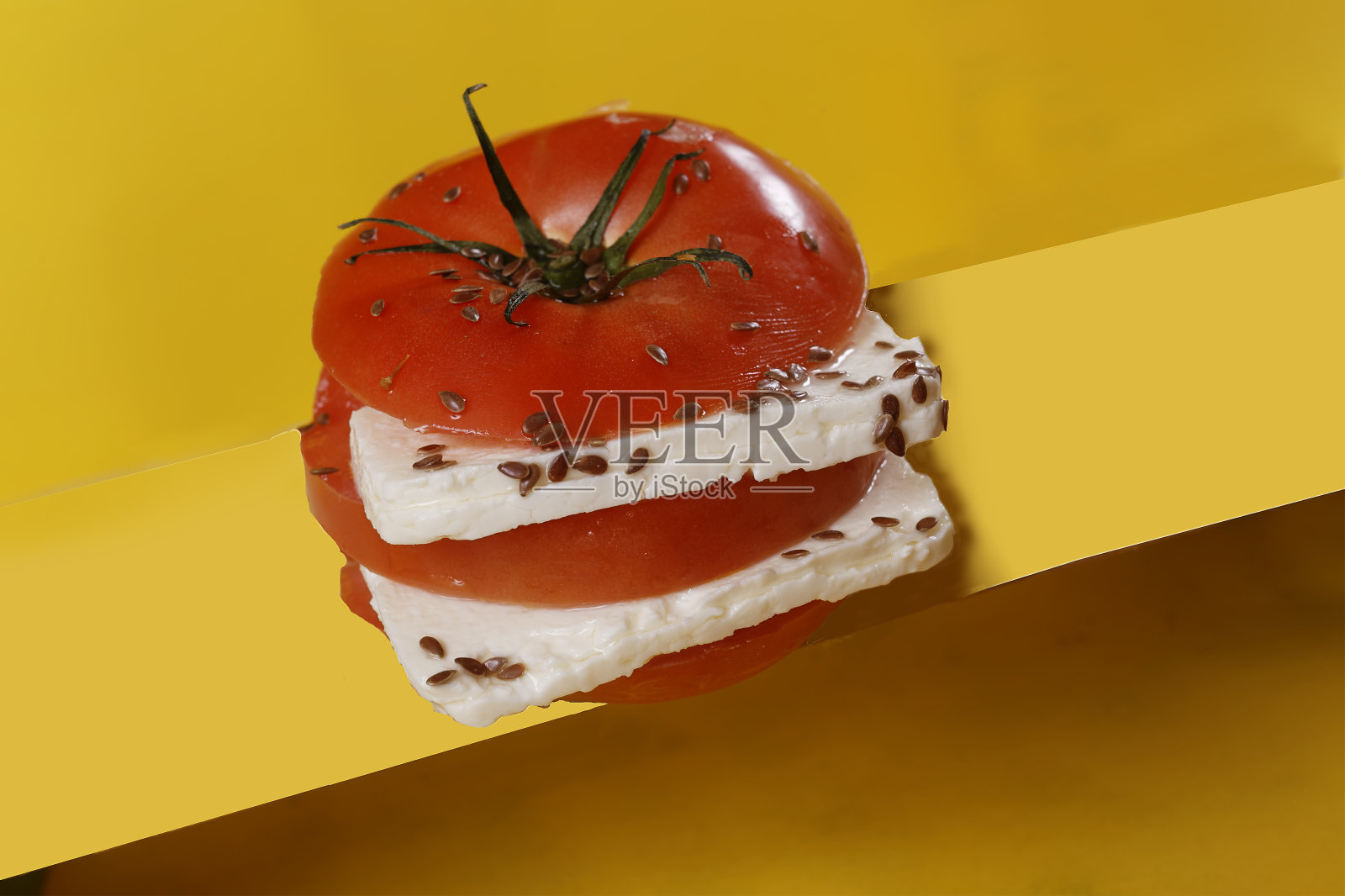 番茄沙拉配帕内拉奶酪和亚麻籽，以黄色、蓝色、绿色和紫色为背景。照片摄影图片