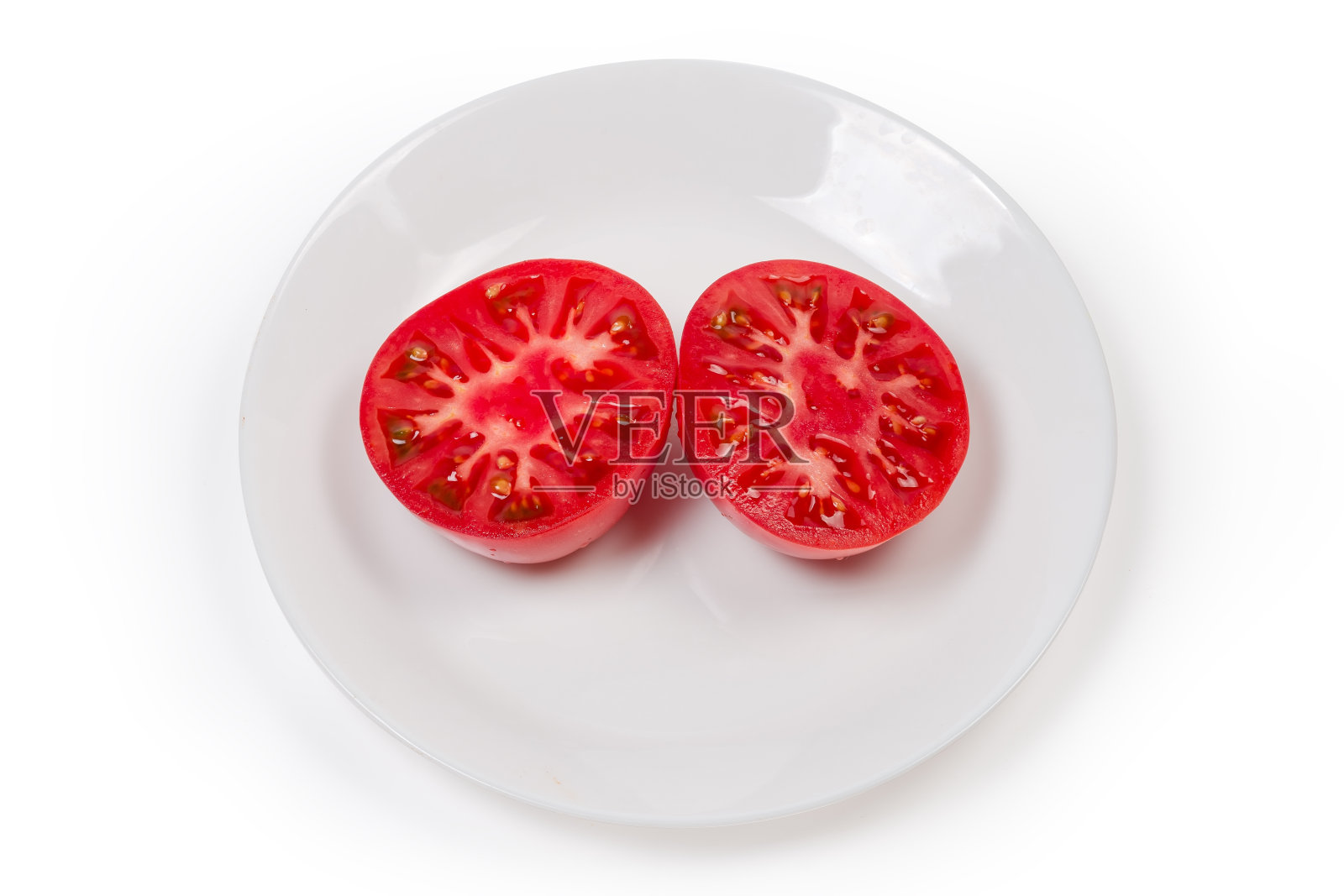 把两半粉红色的番茄放在白色的盘子里照片摄影图片