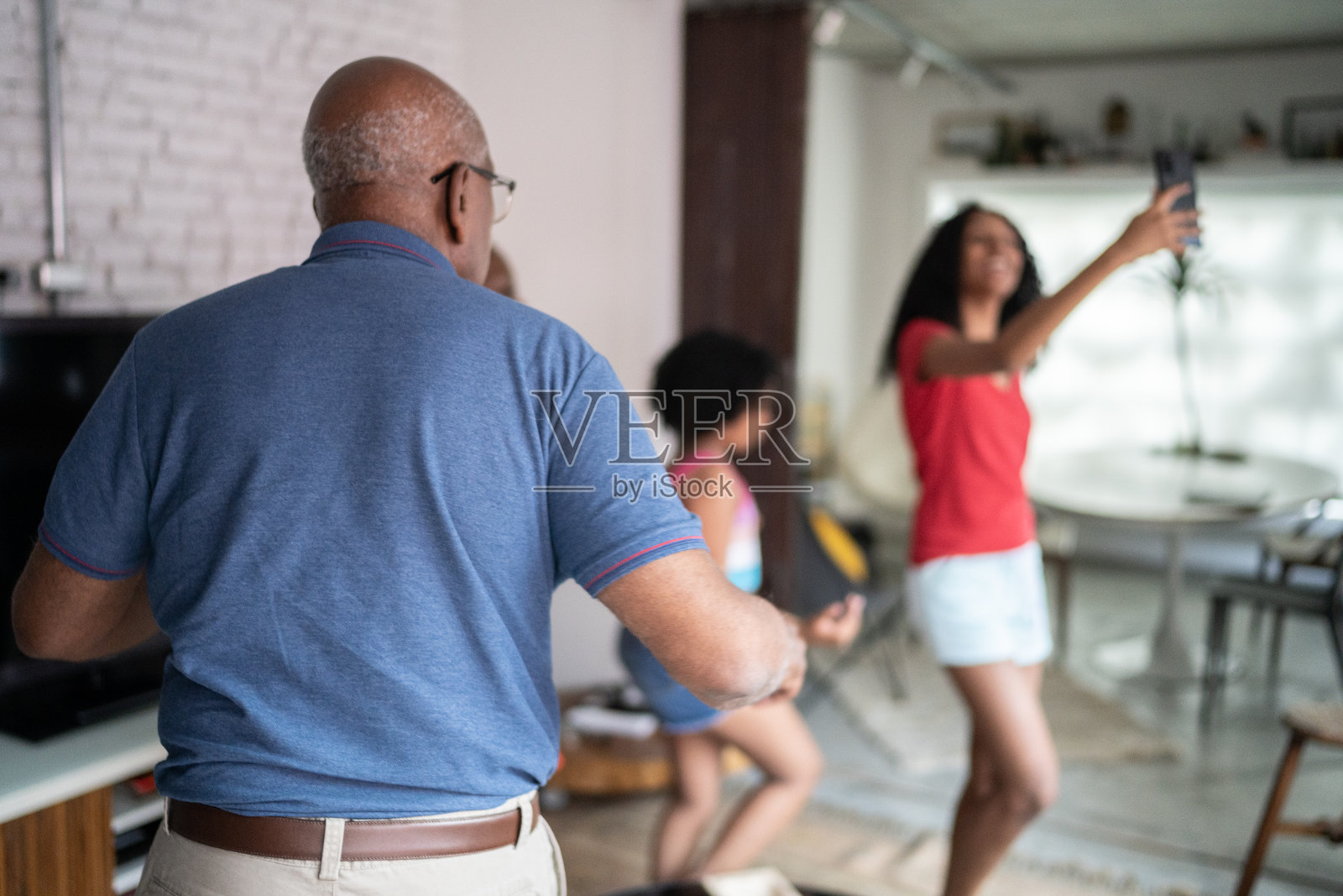 十几岁的女孩用智能手机拍下了一家人在家里一起跳舞照片摄影图片