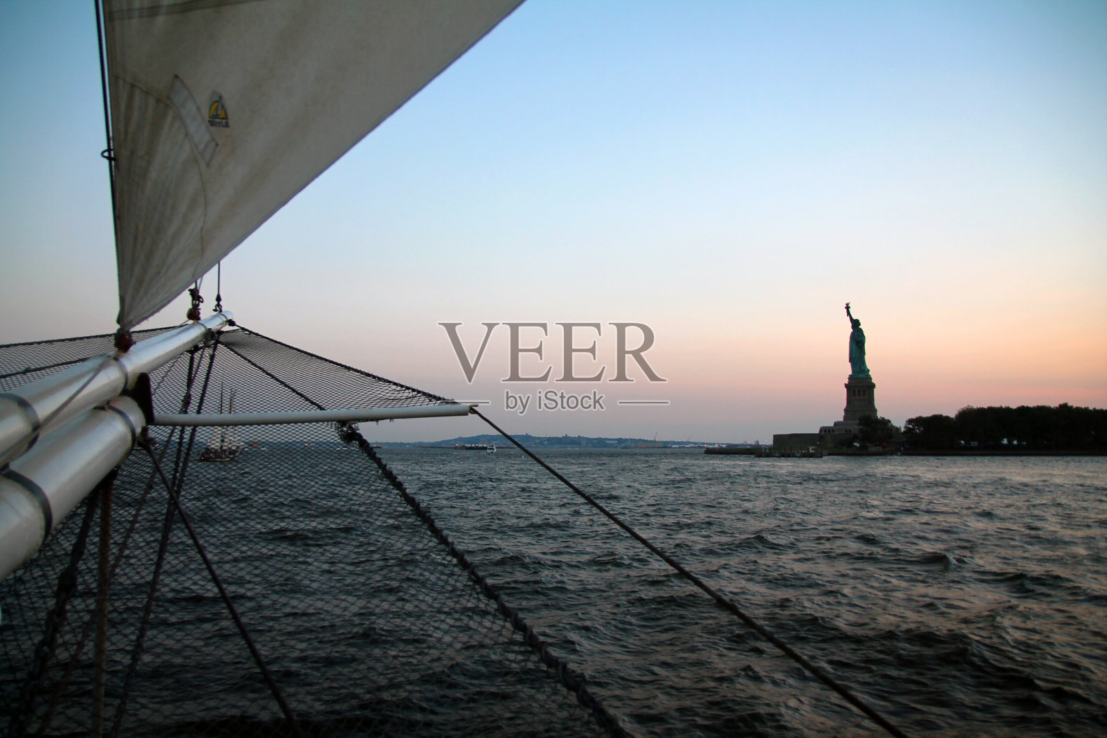 从纽约一艘历史船只上看到的自由女神像背后的日落照片摄影图片