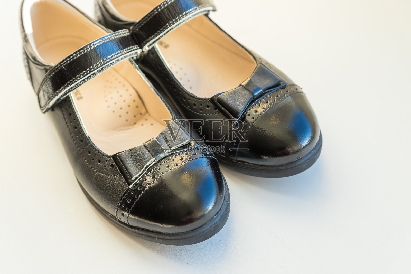 黑色亮皮女孩鞋孤立在白色。经典的儿童皮革学校鞋的女孩，校服。回到学校的概念。一双皮靴。照片摄影图片