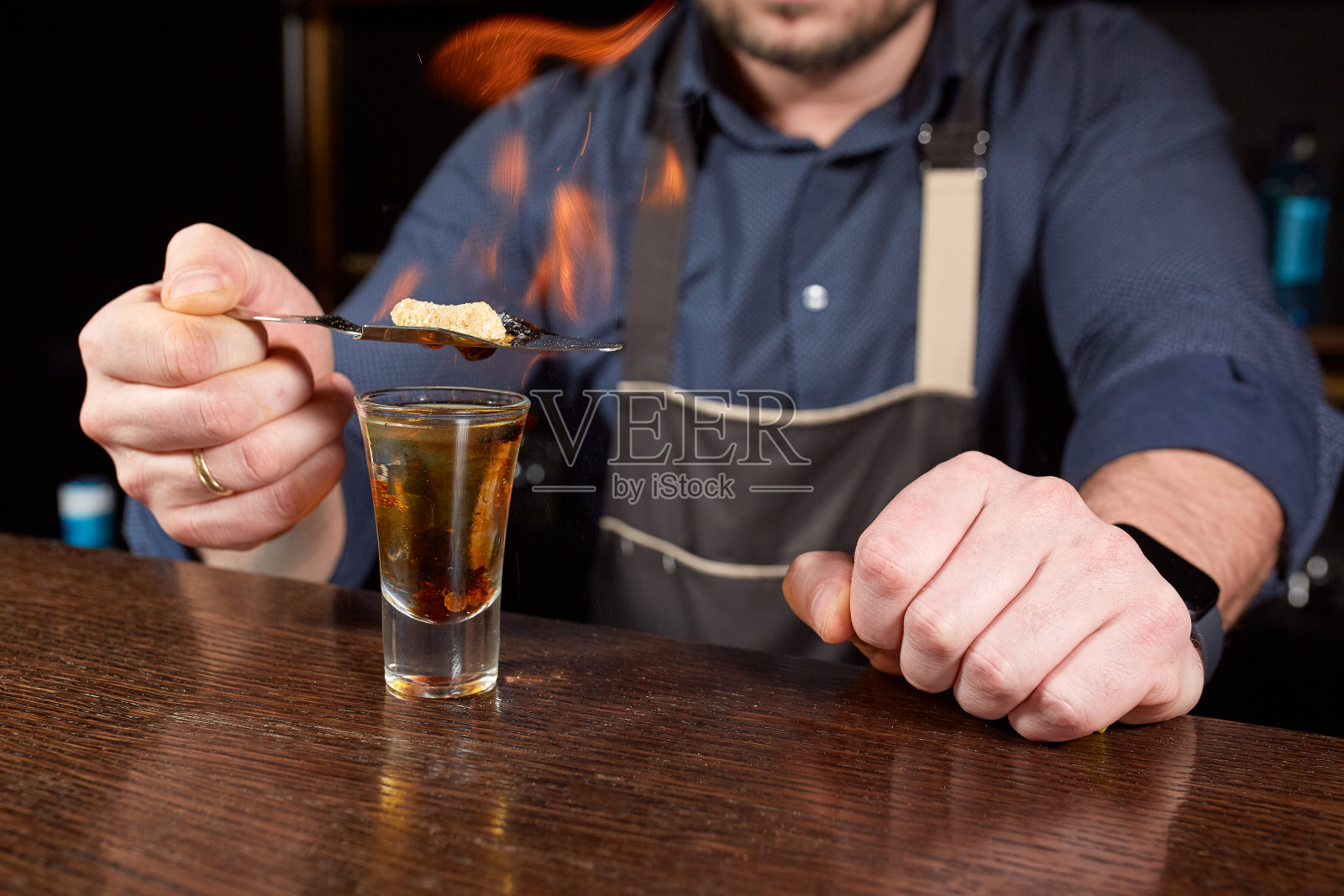 酒吧里火爆的表演。调酒师调制热酒精鸡尾酒，点燃吧台。酒保准备了烈性鸡尾酒。火在酒吧照片摄影图片