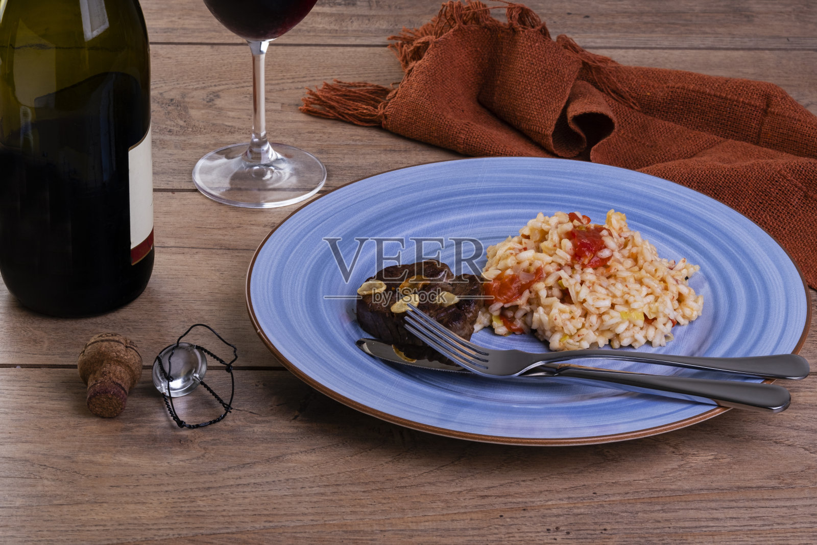 番茄烩饭配韭菜和西西里柠檬一瓶和一杯闪闪发光的葡萄酒照片摄影图片