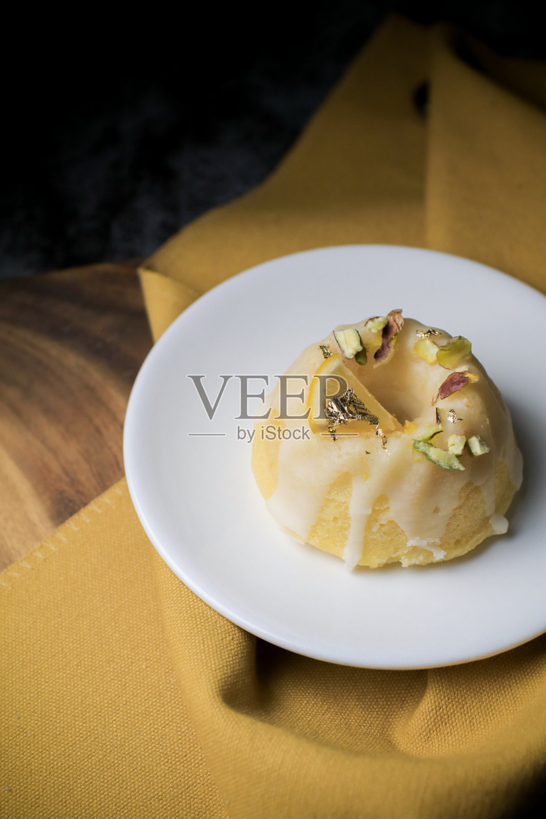 柠檬磅蛋糕作为甜点，放在黑色背景的白色盘子里。这种蛋糕由柠檬汁、黄油和其他配料制成。这蛋糕的味道是酸甜的。照片摄影图片