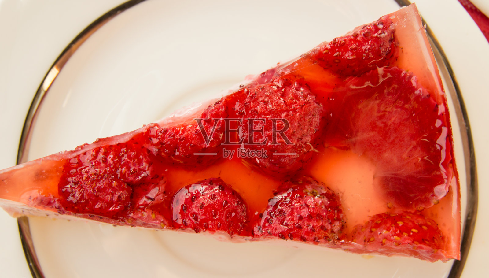 美味的草莓芝士蛋糕放在白色的盘子里，桌上有一张红色方格餐巾，俯视图照片摄影图片