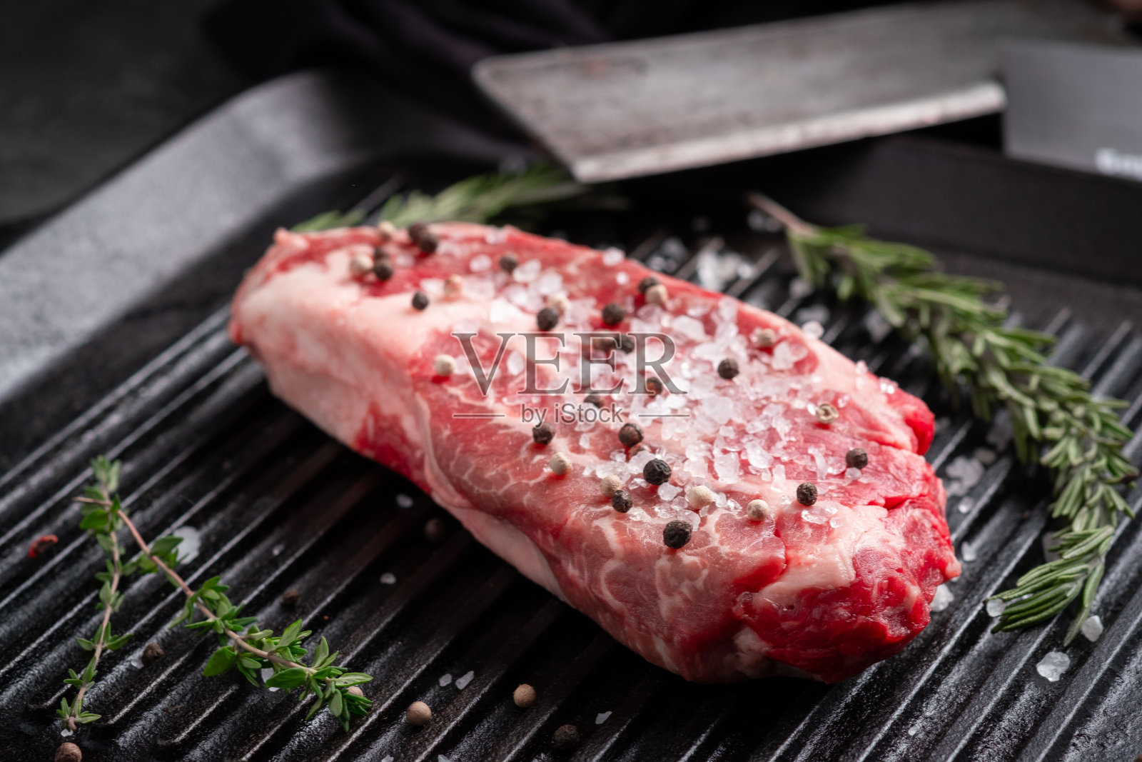 一份完美的生牛排夹头牛肉卷，放在黑色烤盘上，加上调味料照片摄影图片