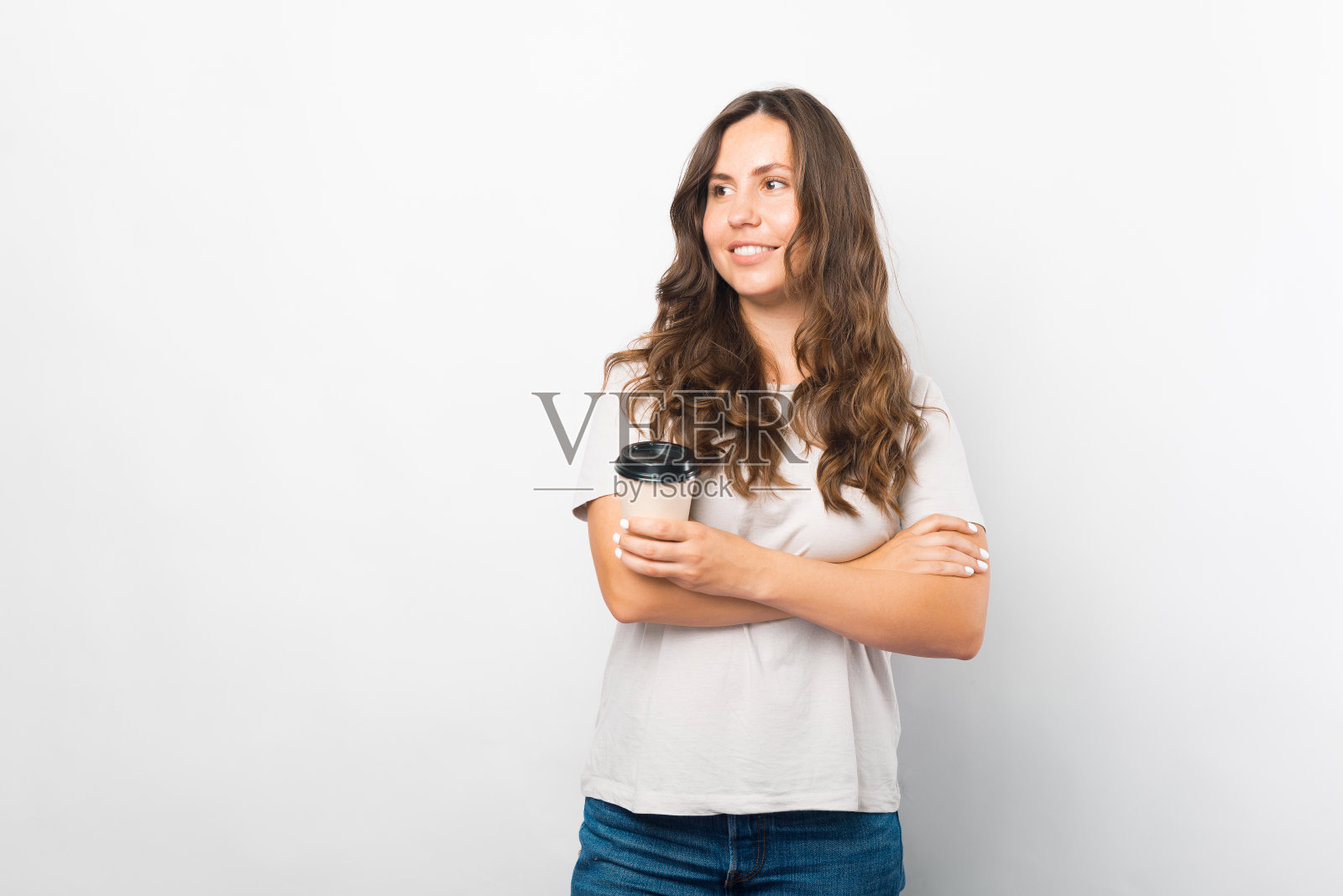 一个微笑的年轻女孩的肖像，手里拿着一杯纸杯咖啡。照片摄影图片