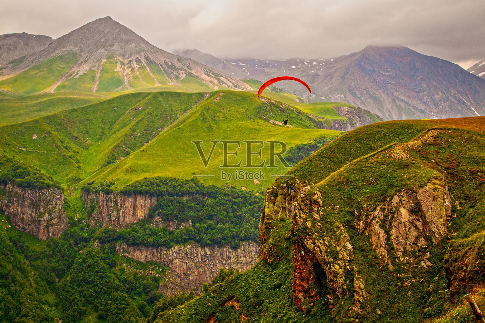 红色parashutef滑翔在格鲁吉亚高加索山脉的山脉和野生峡谷照片摄影图片