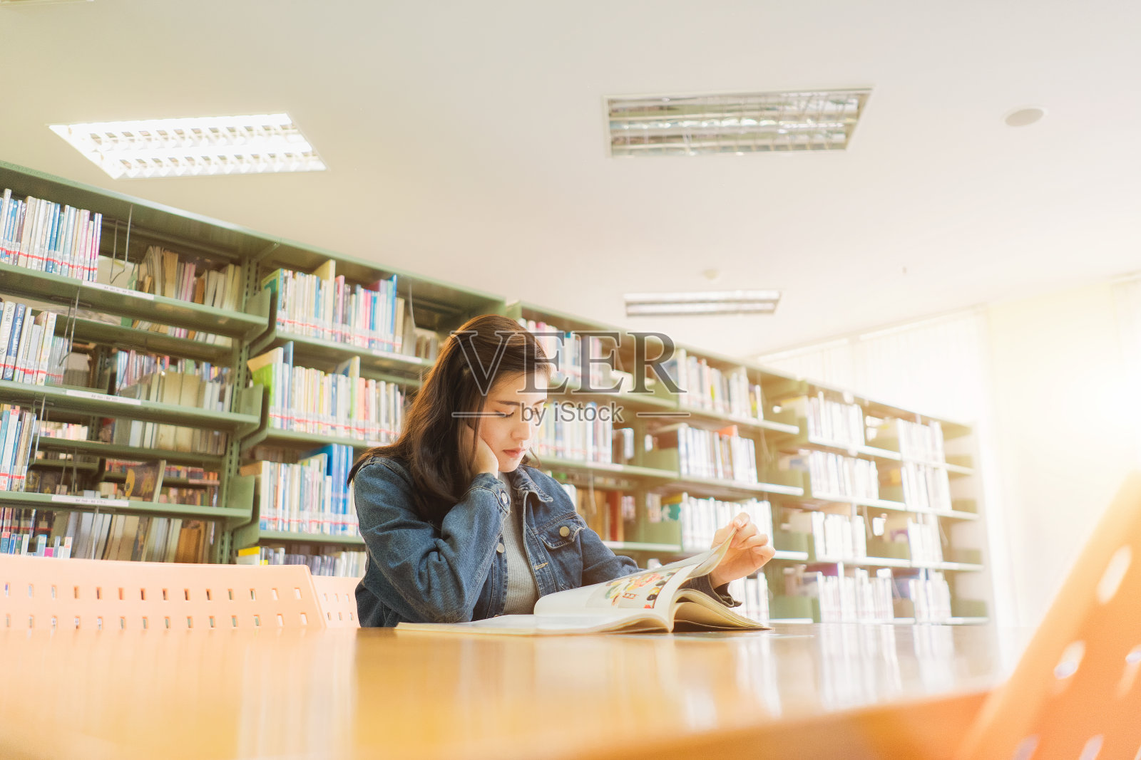 一个亚洲学生正在图书馆阅读和研究，或者为考试学习。照片摄影图片
