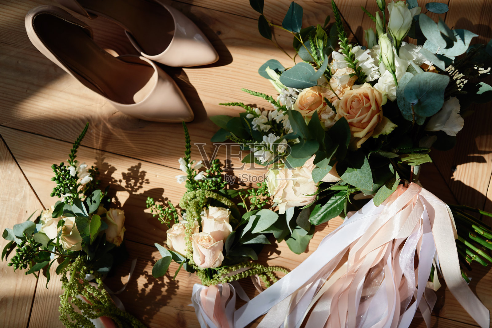 新娘花束粉红色的玫瑰和绿色的缎带，胸花和米色的新娘鞋木制背景，复制空间。结婚的概念。俯视图，平躺，关闭照片摄影图片