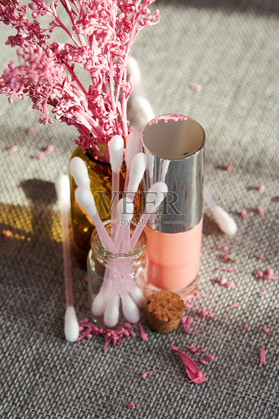 阳光下闪亮的粉红色唇彩瓶和其他化妆品管在化妆桌上。时尚和化妆的背景和符号照片摄影图片