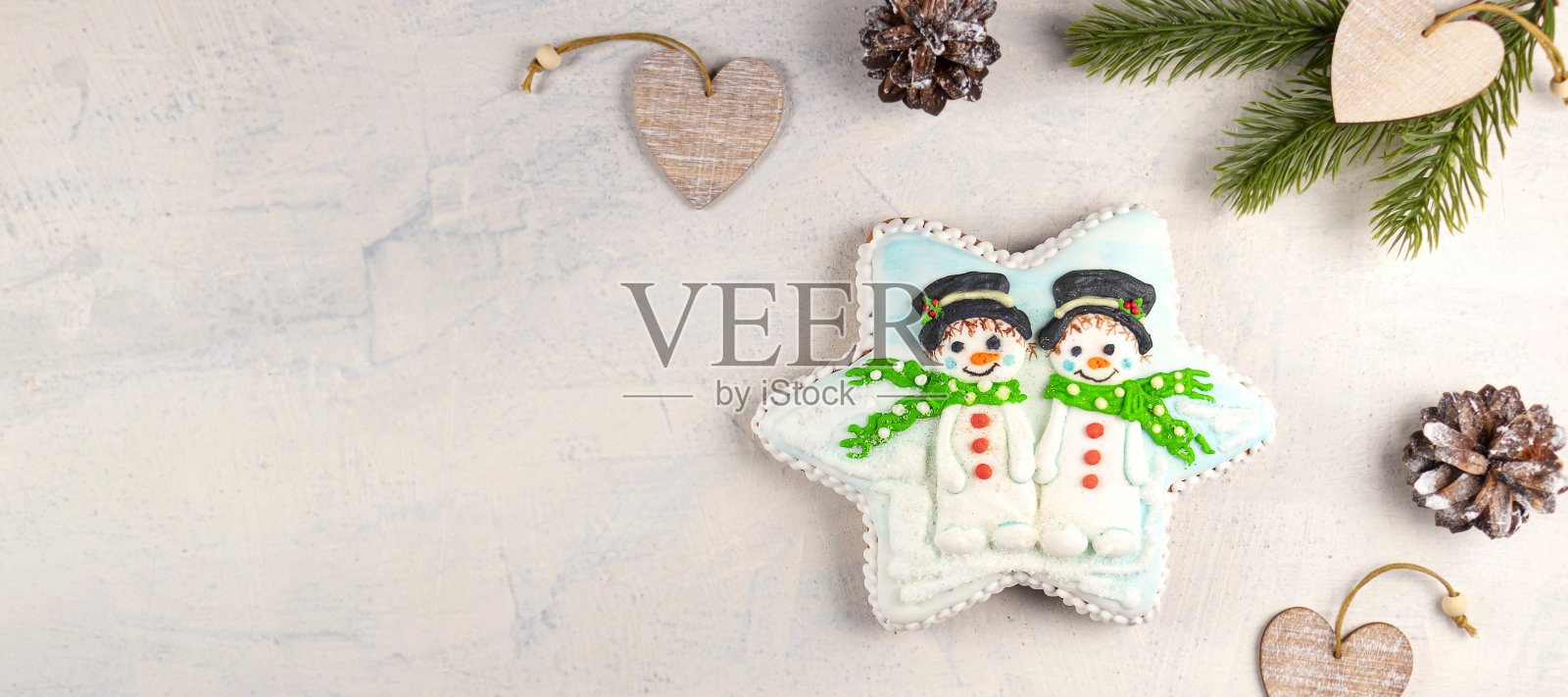 灰色背景上有雪人的圣诞姜饼，还有冷杉树枝和圆锥体。软焦点照片摄影图片