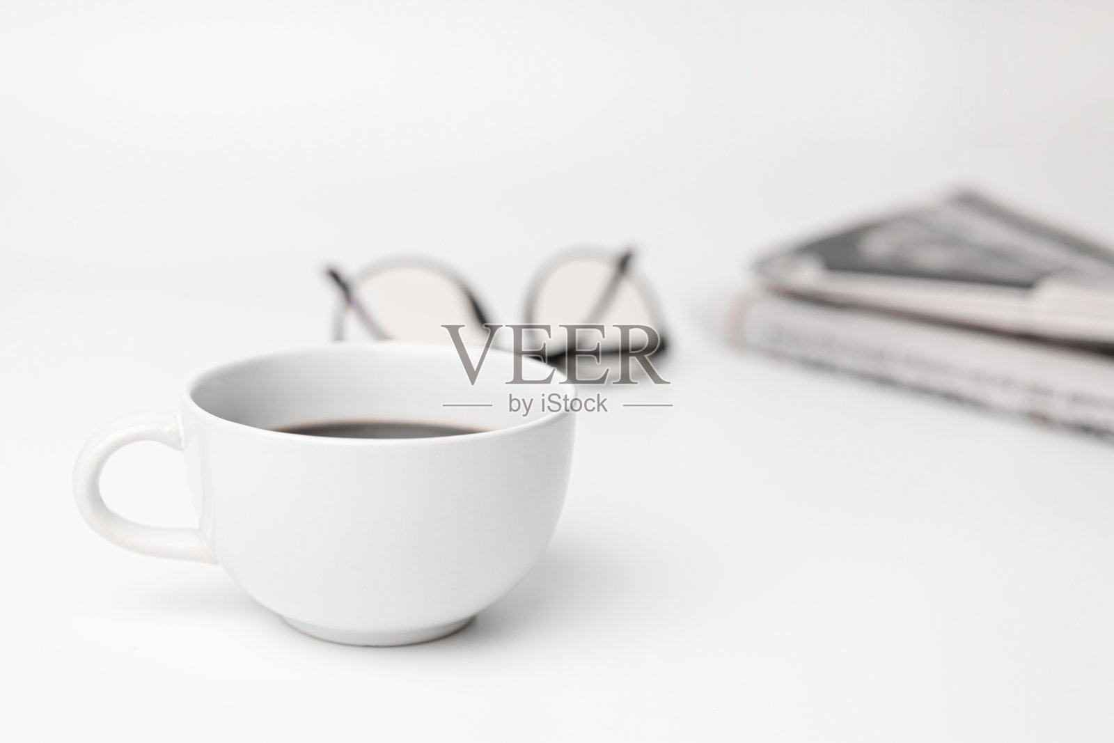 白色的桌子上放着咖啡杯、玻璃杯、报纸照片摄影图片