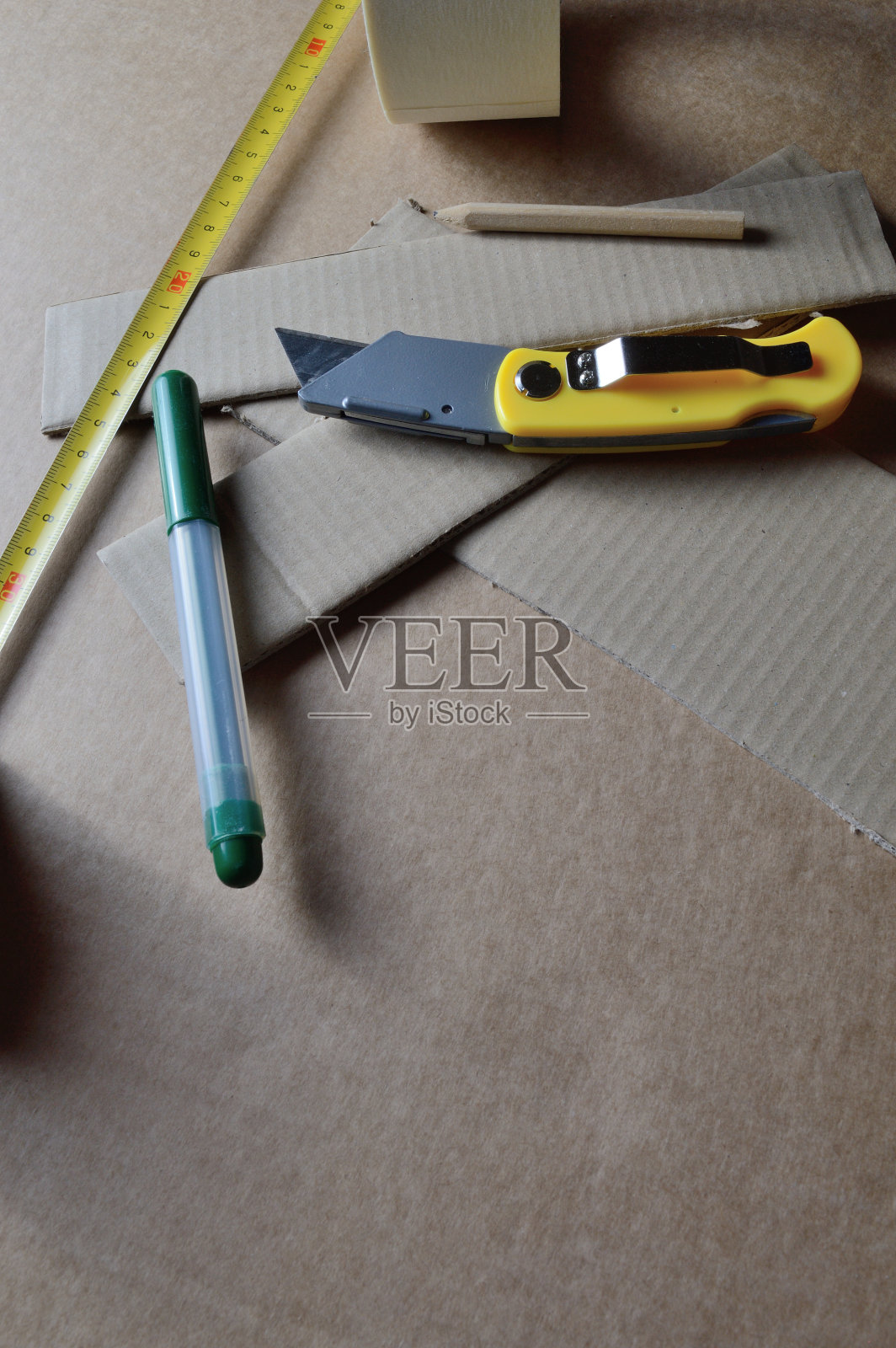 用硬纸板工作的工具放在有硬纸板屑的桌子上。照片摄影图片