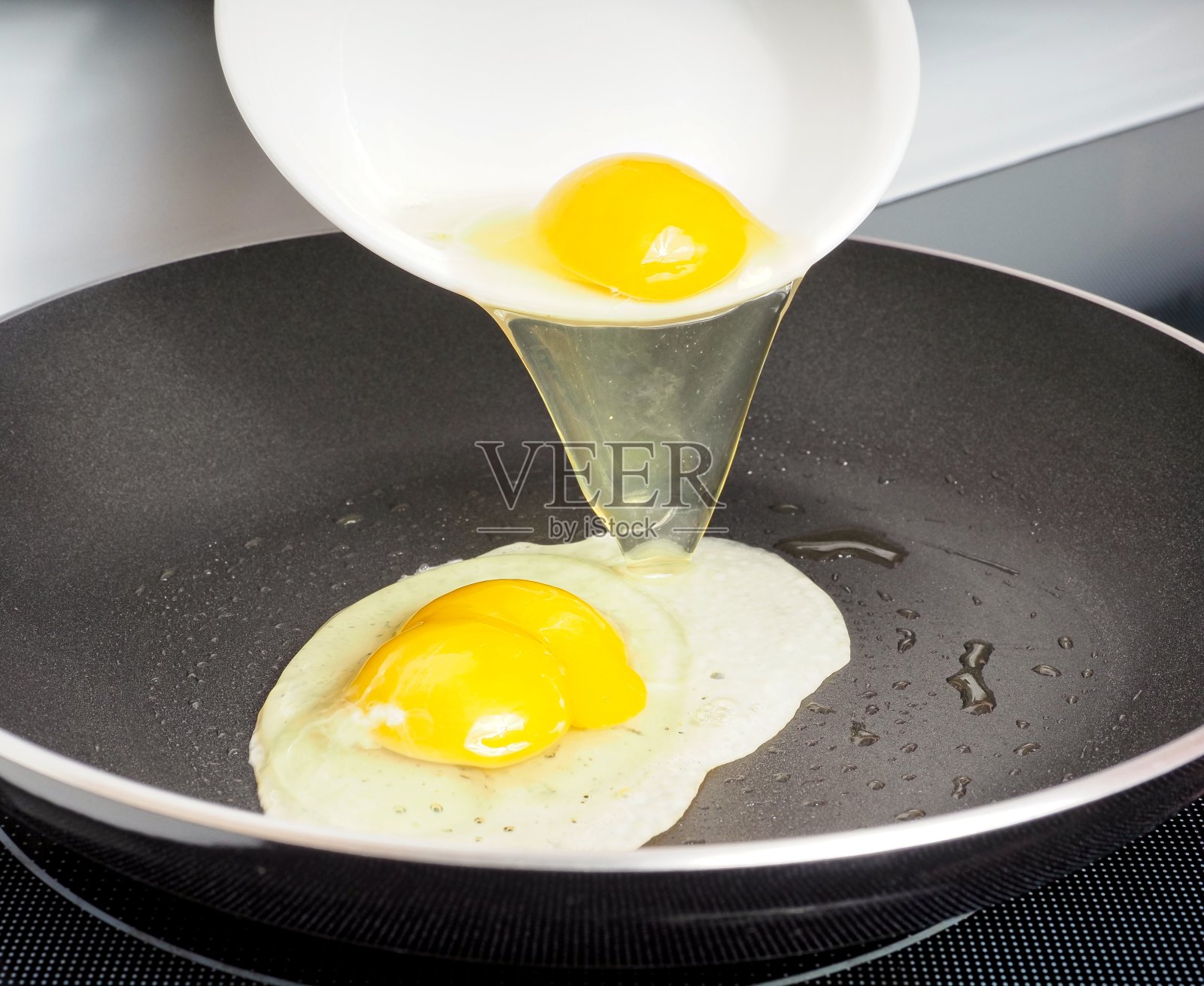 用橄榄油在不粘锅里煎鸡蛋照片摄影图片