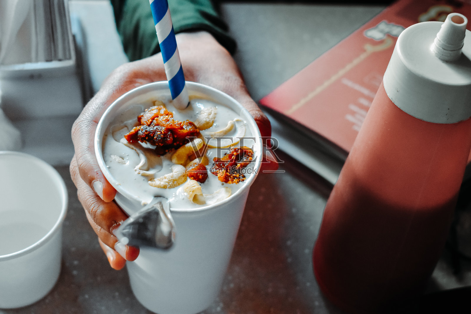 在咖啡馆里，手拿一杯干果奶昔。照片摄影图片