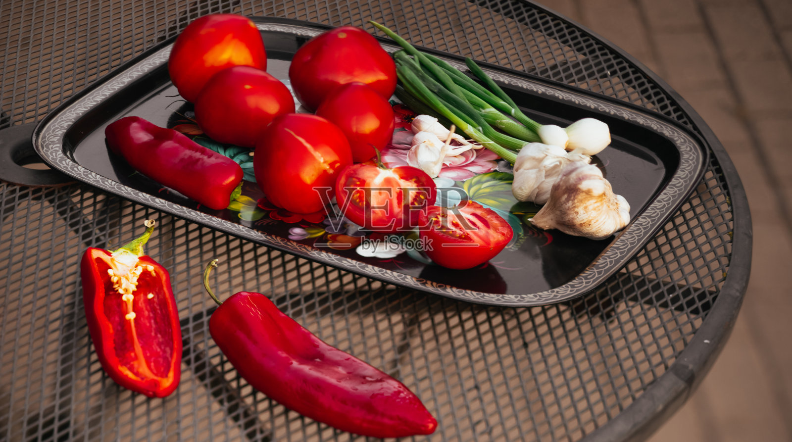 西红柿，大蒜，青葱放在盘子里。切辣椒。黑色的表。照片摄影图片