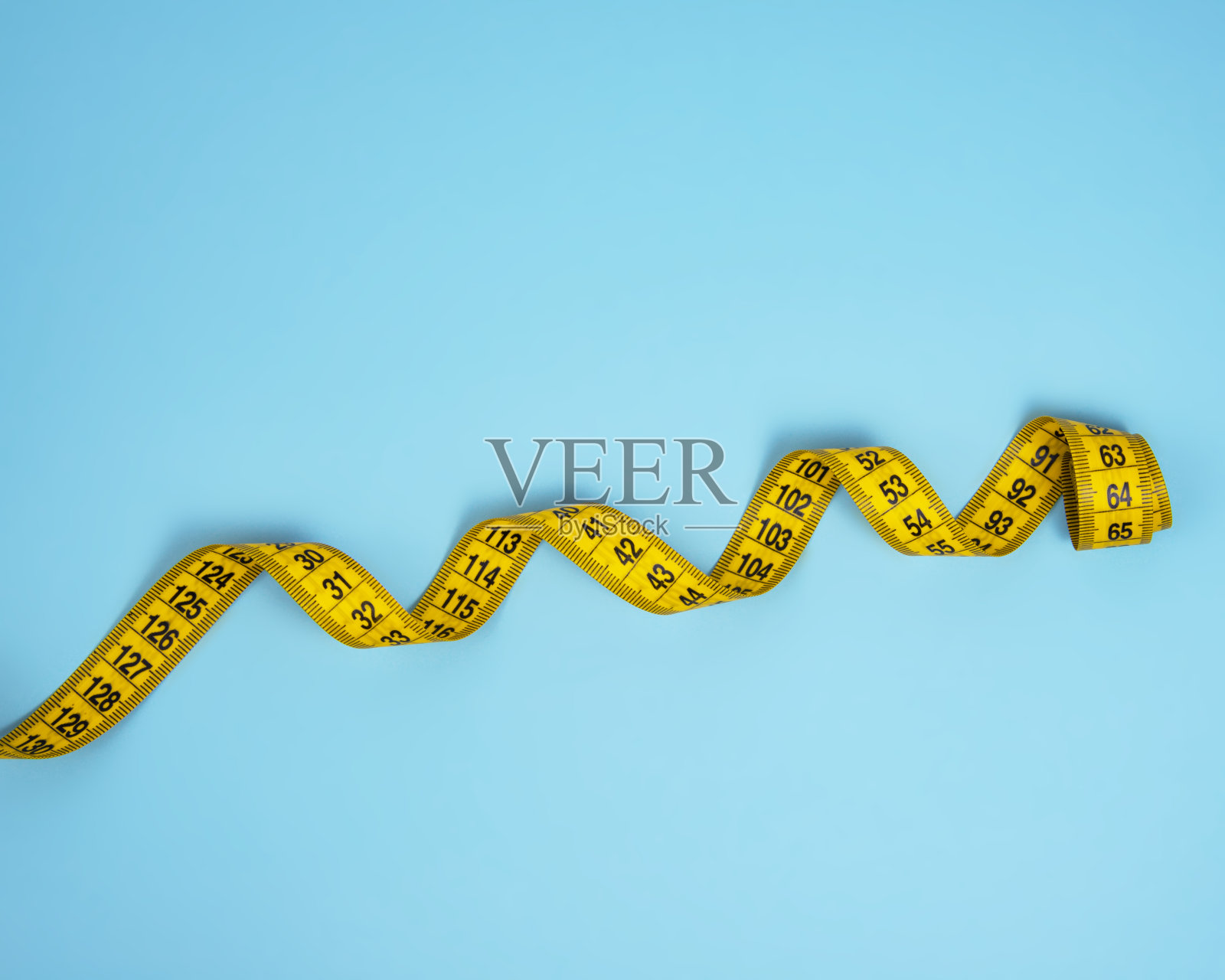 黄色螺旋卷尺测量在蓝色明亮的背景照片摄影图片