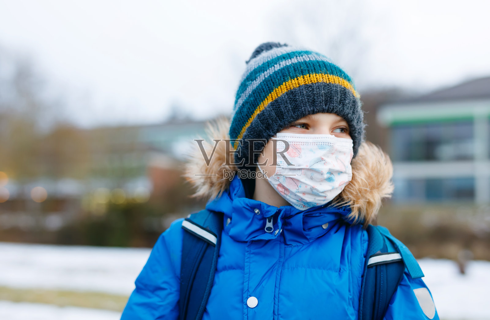 一个男孩戴着ffp医用口罩在上学的路上孩子背包背包。学生在寒冷的秋冬季穿着暖和的衣服。冠状病毒大流行期间的封锁和隔离时间照片摄影图片
